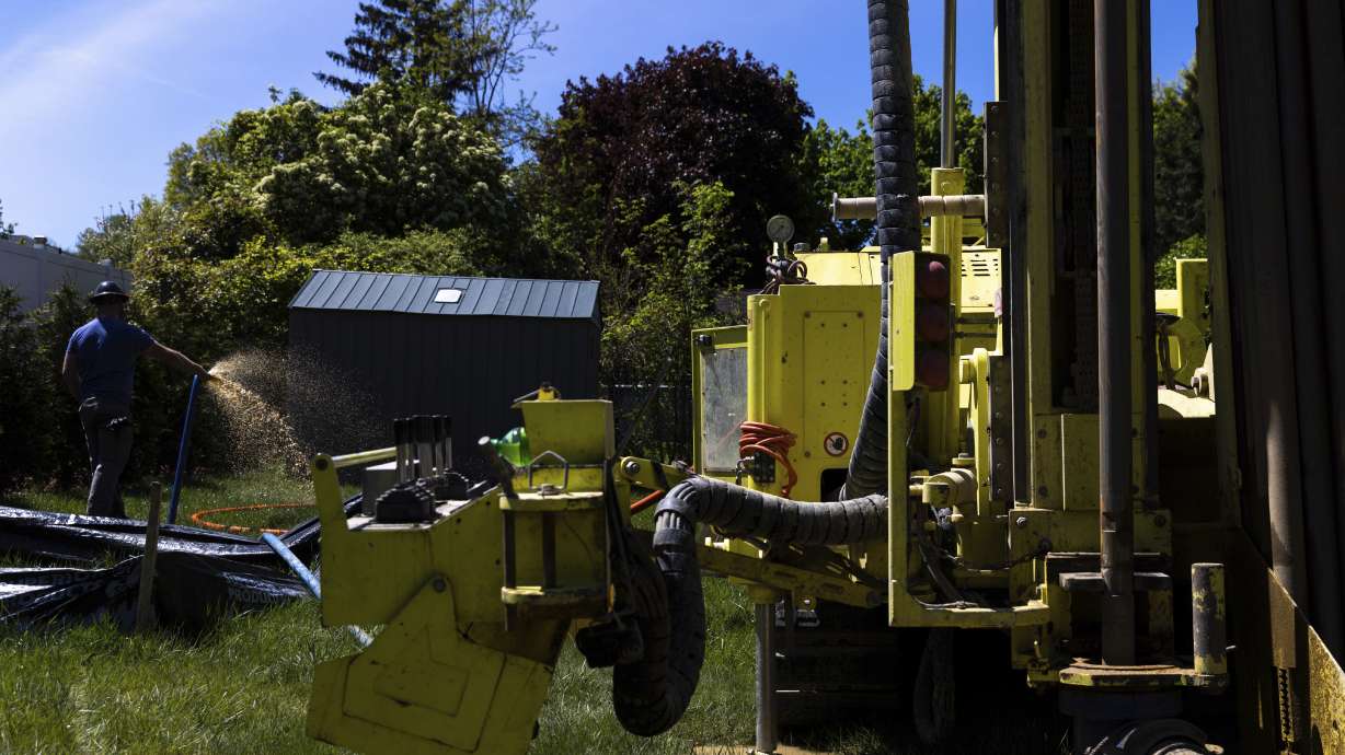 A Dandelion Energy employee sprays excess groundwater back on the lawn during the installation of a geothermal heat pump system at a home in White Plains, N.Y., May 8. A water-filled loop is installed several hundred feet deep in the yard to either carry heat away from or into the house depending on season. Industry experts see the technology becoming increasingly popular in the coming years.