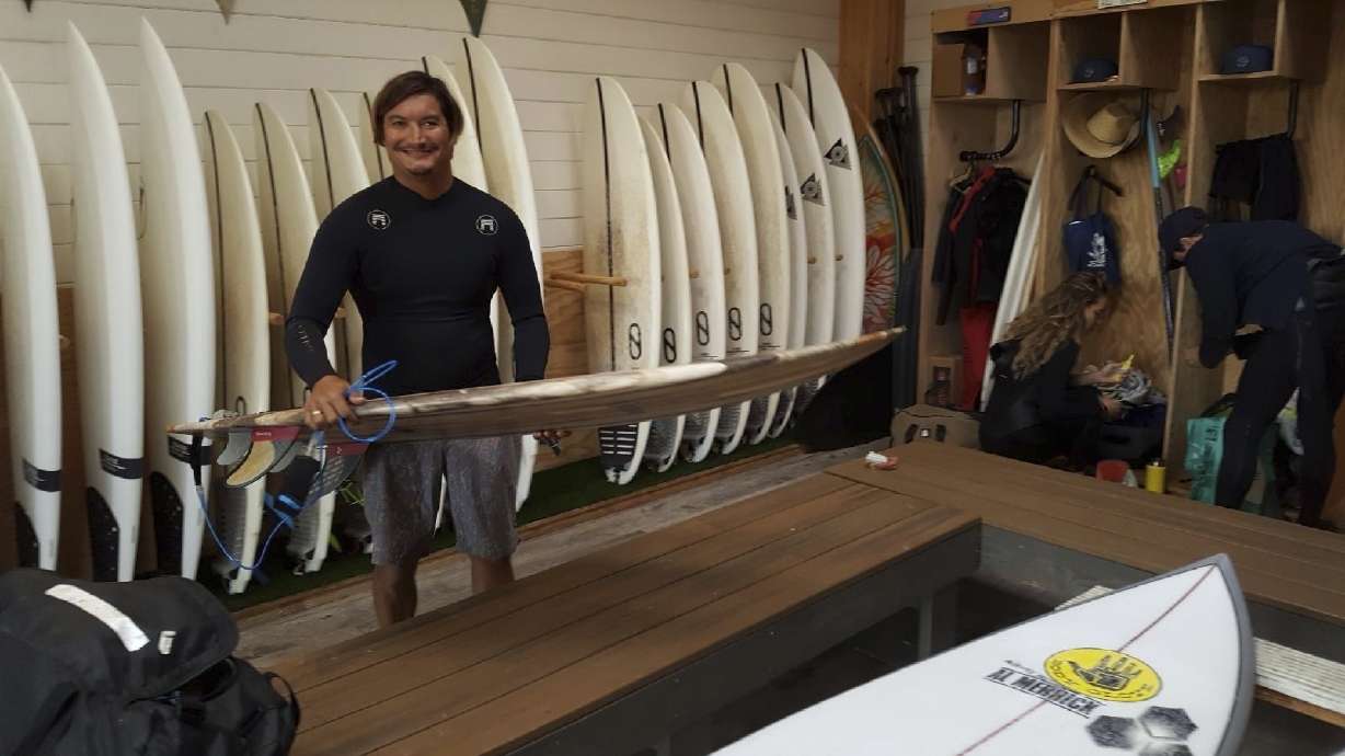 This May 19, 2019 photo provided by Dr. John Jones shows Mikala Jones at Surf Ranch in Lemoore, Calif., holding a surfboard his brother Daniel Jones made using material from the agave plant. Mikala Jones, a Hawaii surfer known for shooting awe-inspiring photos and videos from the inside of barreling waves, has died at the age of 44 after a surfing accident in Indonesia.