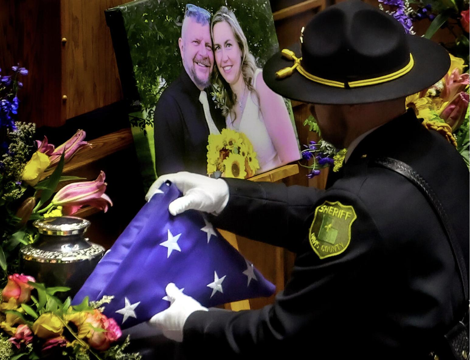 A flag is placed next to an urn during the memorial service for Davis County Sheriff's Cpl. Steven Lewis and deputy Jennifer Turner at the Dee Events Center in Ogden on Friday. Lewis and Turner were killed in a motorcycle crash July 3, three days after they were married.