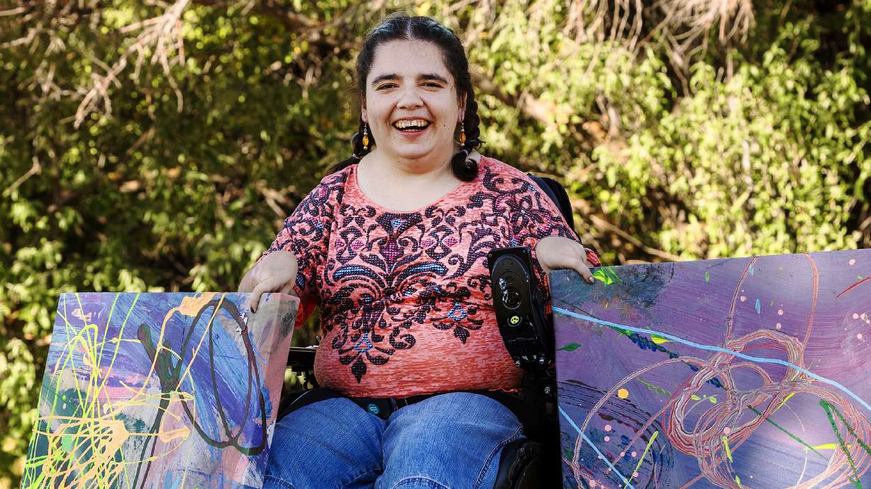 Kaya Eccles holds two paintings in Logan on Wednesday. After making adaptive technology for his art students, Michael Bingham helps Utahns with disabilities pursue their passions.