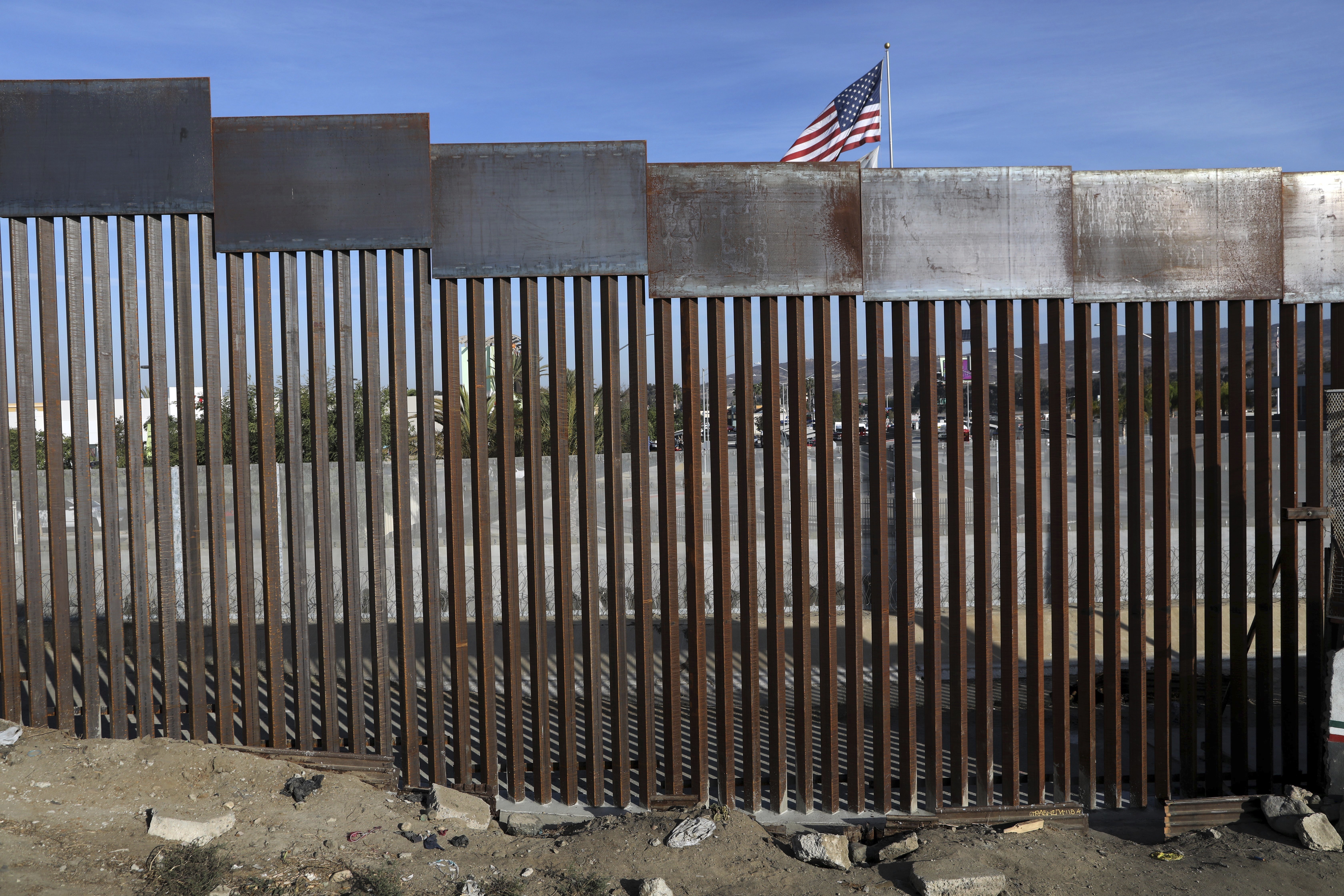 A United States flag flies behind the border fence in Tijuana, Mexico, Nov. 21, 2018. Nearly a thousand migrants formed a group Saturday, heading north together to reach the U.S.