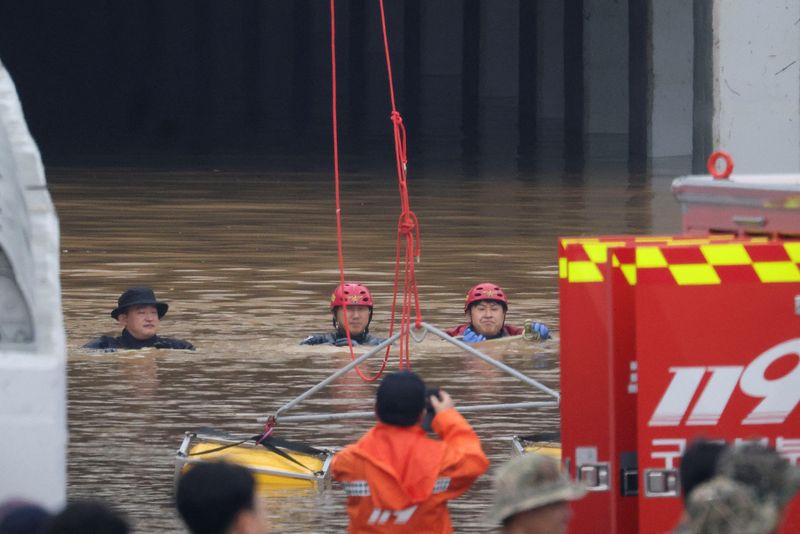 Rescuers conduct a search operation along a road submerged by floodwaters leading to an underground tunnel in Cheongju, South Korea, Sunday.