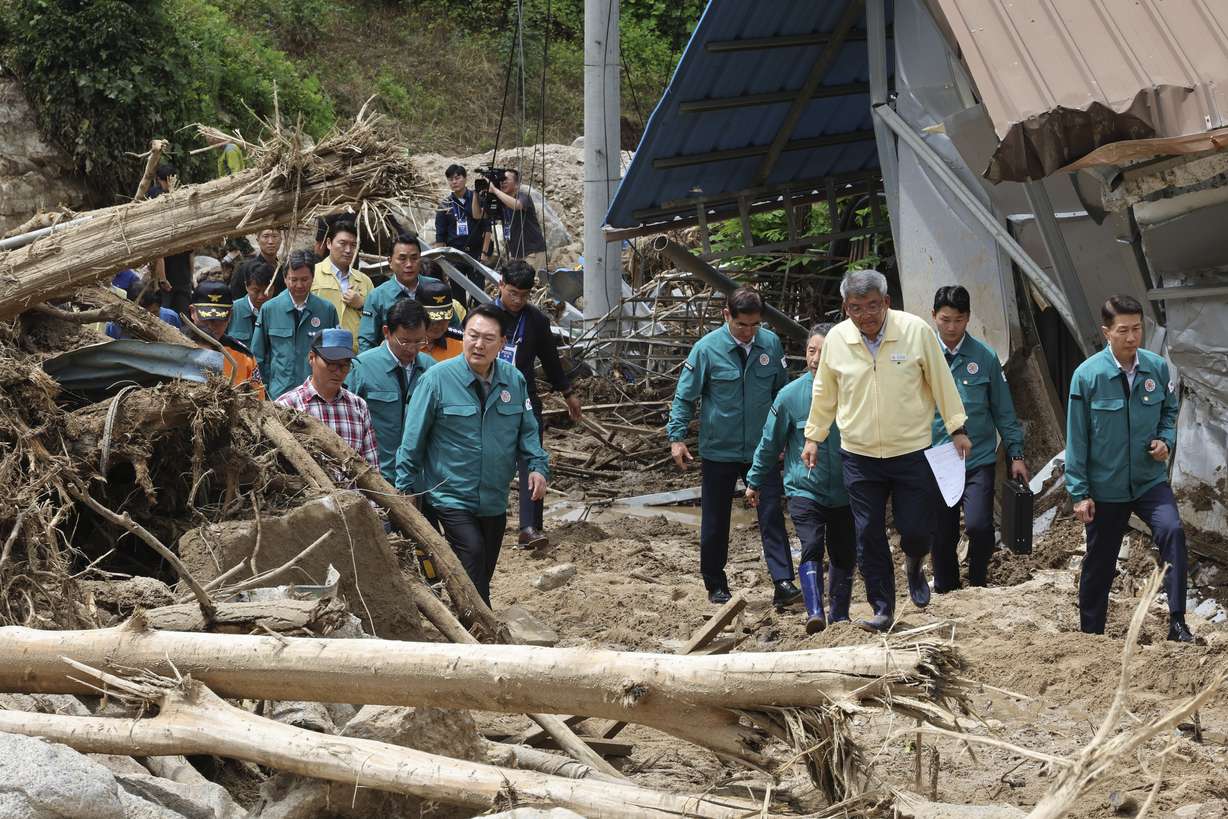 South Korean President Yoon Suk Yeol, third from left, looks around a flood damaged area in Yecheon, South Korea, Monday. Heavy downpours lashed South Korea a ninth day on Monday as rescue workers struggled to search for survivors.