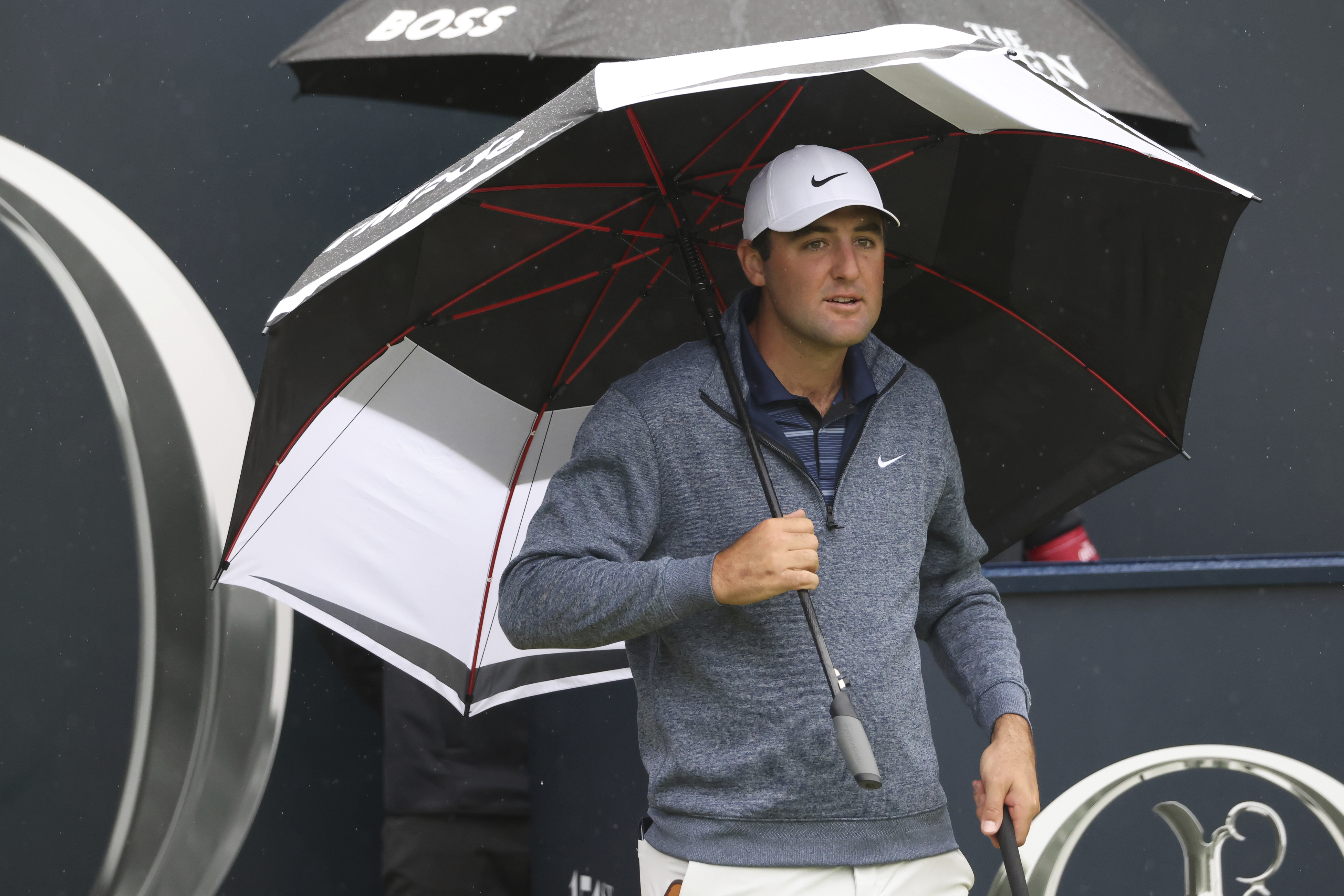 United States' Scottie Scheffler waits under an umbrella on the 1st tee as light rain falls during a practice round for the British Open Golf Championships at the Royal Liverpool Golf Club in Hoylake, England, Tuesday, July 18, 2023. The Open starts Thursday, July 20. 