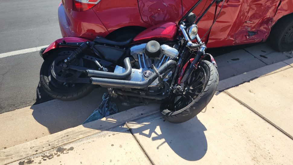 A Harley-Davidson is partially crushed under a Honda Fit after a crash at the corner of Red Hills Drive and 2450 East, St. George, Wednesday. The motorcycle and its passenger were dragged across the road. 