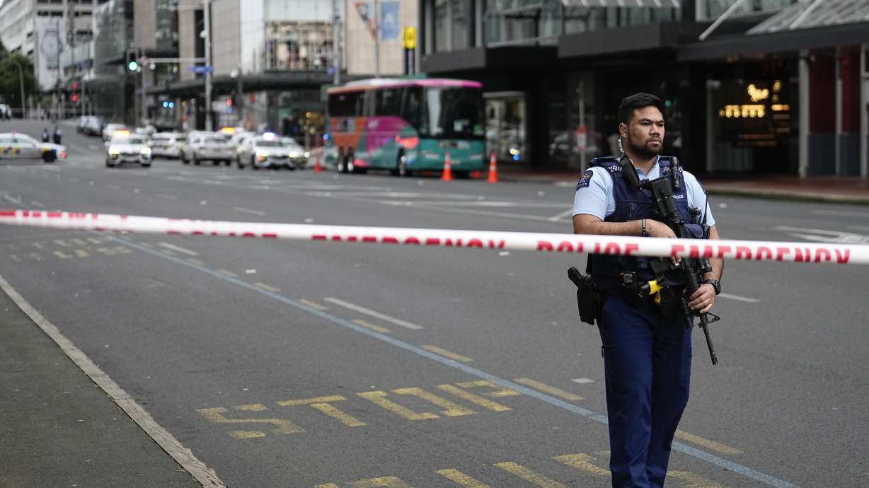 An armed New Zealand police officer stands at a road block in the central business district following a shooting in Auckland, New Zealand, Thursday, July 20, 2023. New Zealand police are responding to reports that a gunman has fired shots in a building in downtown Auckland.