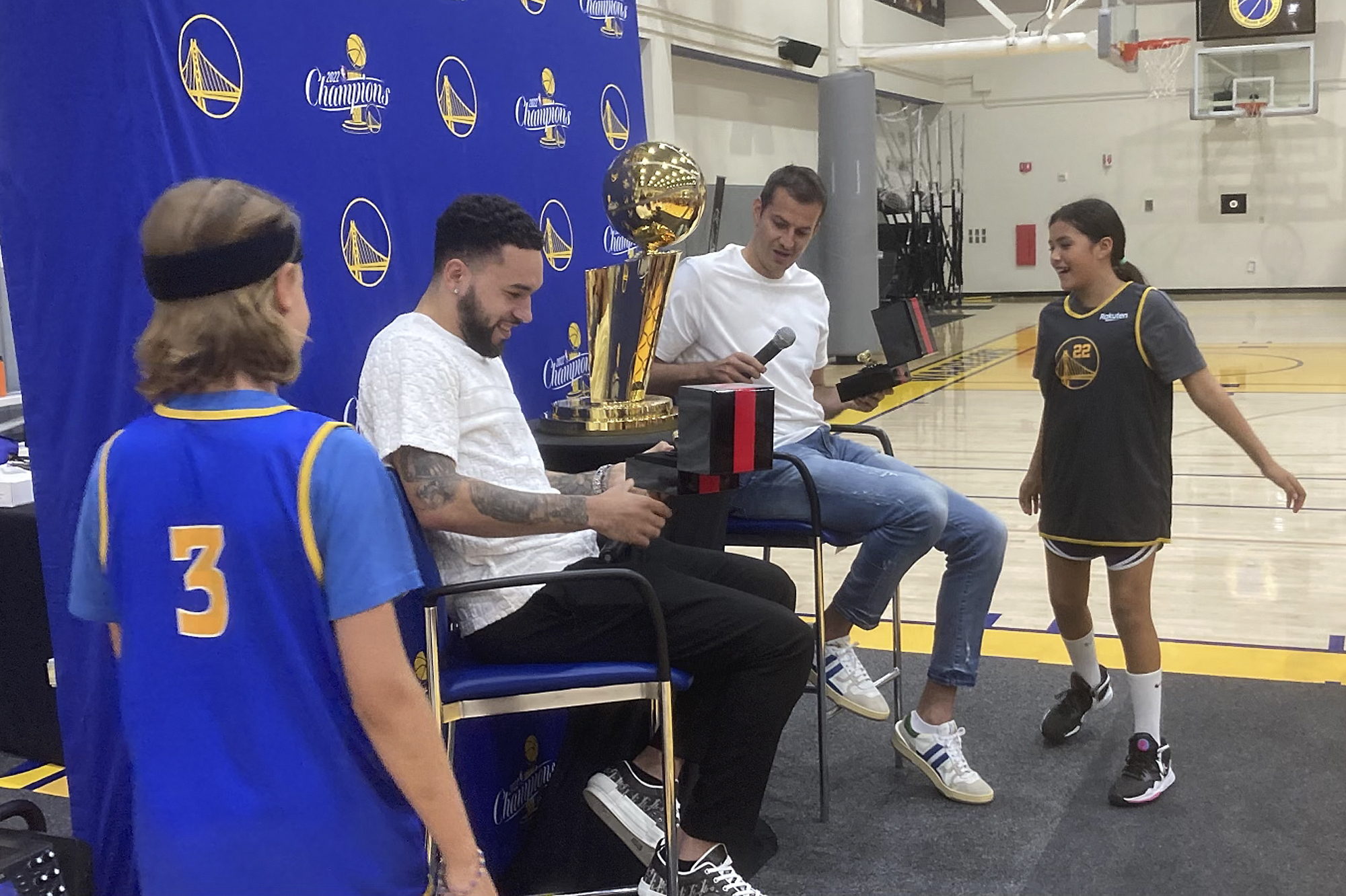 Golden State Warriors youth campers Will McCloskey, left, and Amari Chiefelk, right, present former Warriors players Nemanja Bjelica and Chris Chiozza, second from left, with their 2022 NBA championship rings in a special ceremony, Wednesday, July 19, 2023, in Oakland, Calif. Typically, the Warriors present former players with their rings in a pregame on-court ceremony when they come through town with an opposing organization, but these two were playing overseas.