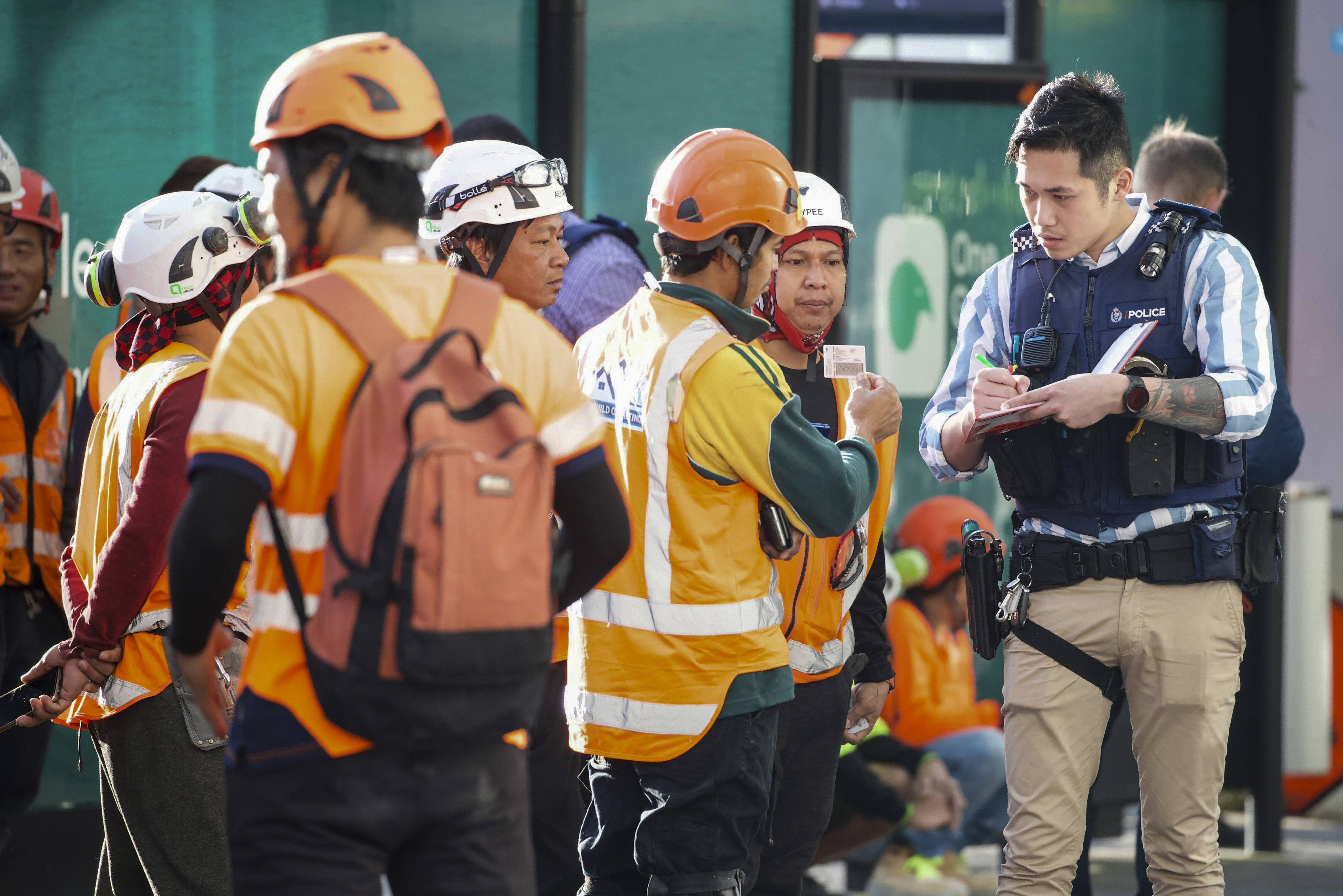 Police interview construction workers in the central business district following a shooting in Auckland, New Zealand, Thursday, July 20, 2023. A gunman killed and injured people at a construction site in New Zealand’s largest city, as the nation prepared to host games in the FIFA Women’s World Cup soccer tournament, authorities said.