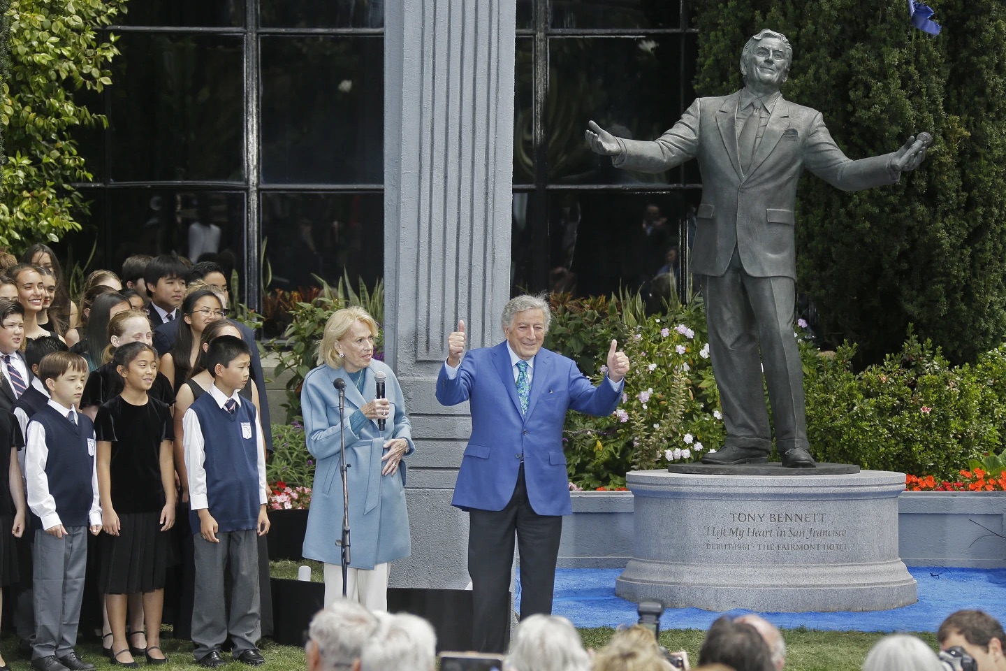 Tony Bennett gives a thumbs up as members San Francisco Boys and Girls Chorus and city and state Chief of Protocol Charlotte Shultz, left, look on, after Bennett's statue was unveiled outside the Fairmont Hotel Aug. 19, 2016, atop Nob Hill in San Francisco. Bennett died Friday. He was 96.