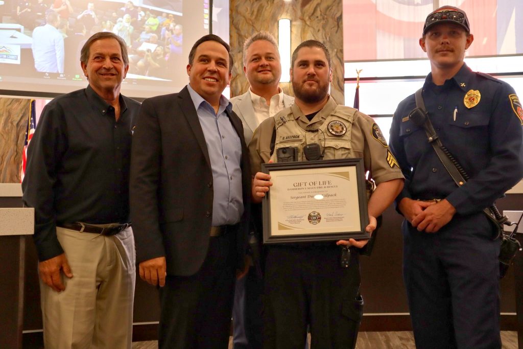 L-R: Washington County Commissioners Gil Almquist, Victor Iverson, Adam Snow (background), Washington County Sheriff’s Sgt. Dusty Killpack and Dammeron Valley Fire and Rescue Battalion Chief Ryan D’ambrosio stand for a group photo following Killpack receiving a Gift of Life Award for the part he played in saving a man from a burning car on June 9 on state Route 18, St. George, Utah, Tuesday.