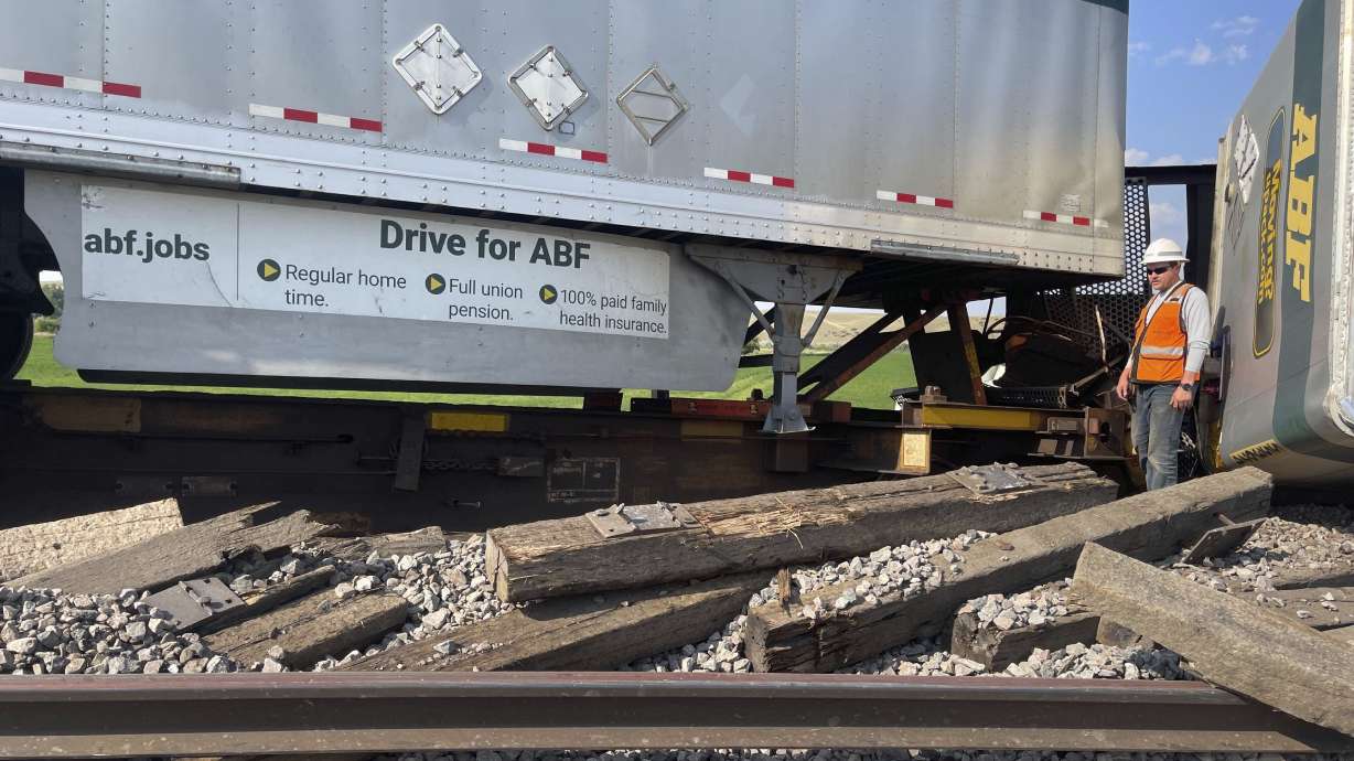 A railroad worker stands among derailed freight cars from a BNSF Railway train that derailed east of Havre, Montana on Friday. Local officials said 25 cars derailed but no one was injured.