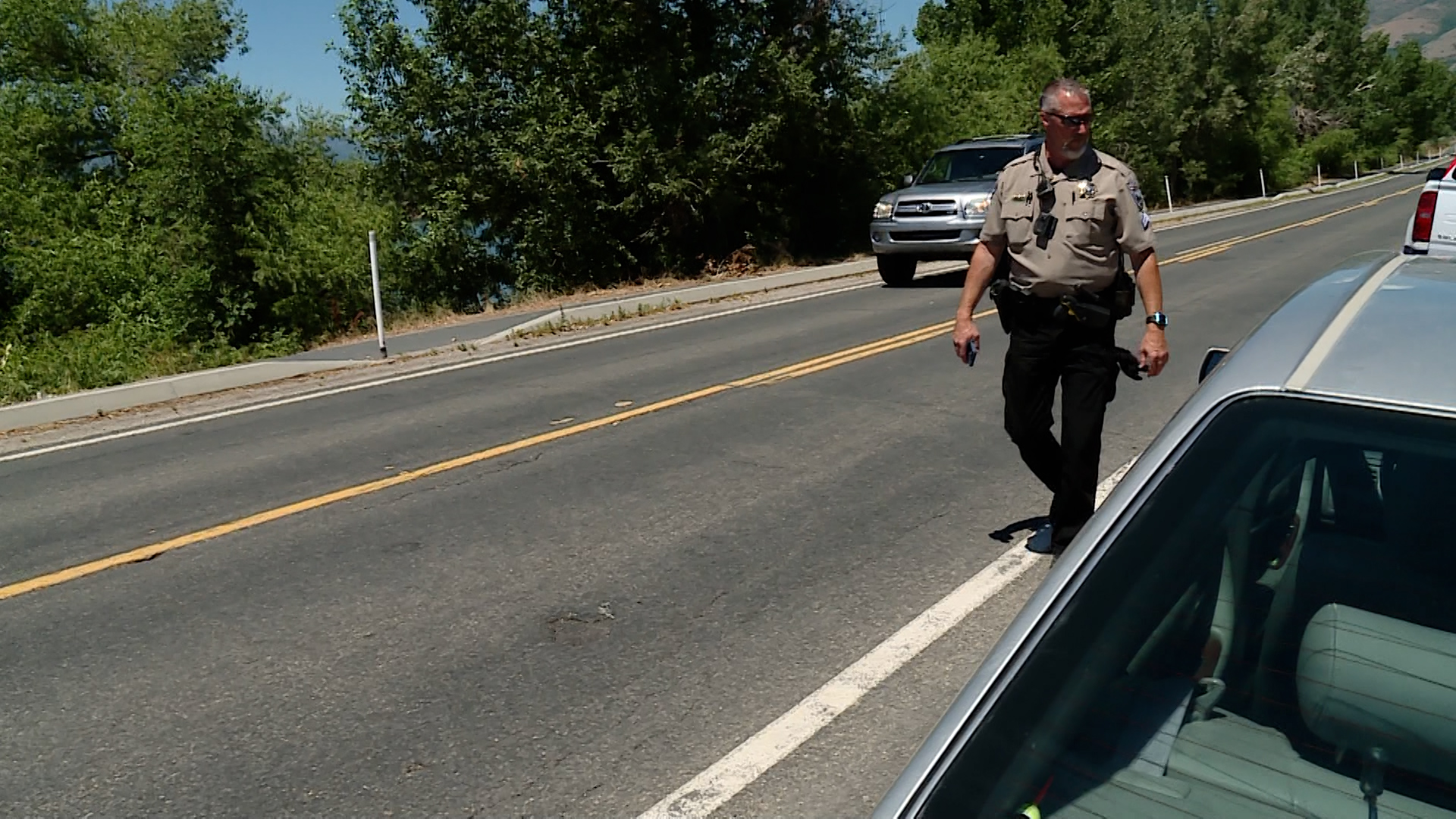 Weber County Sheriff's Cpl. Jim Kortright looks to see if any cars are illegally parking at the reservoir. As more and more people try to cool off at Utah's lakes and reservoirs, more police patrol the area to keep everyone safe.