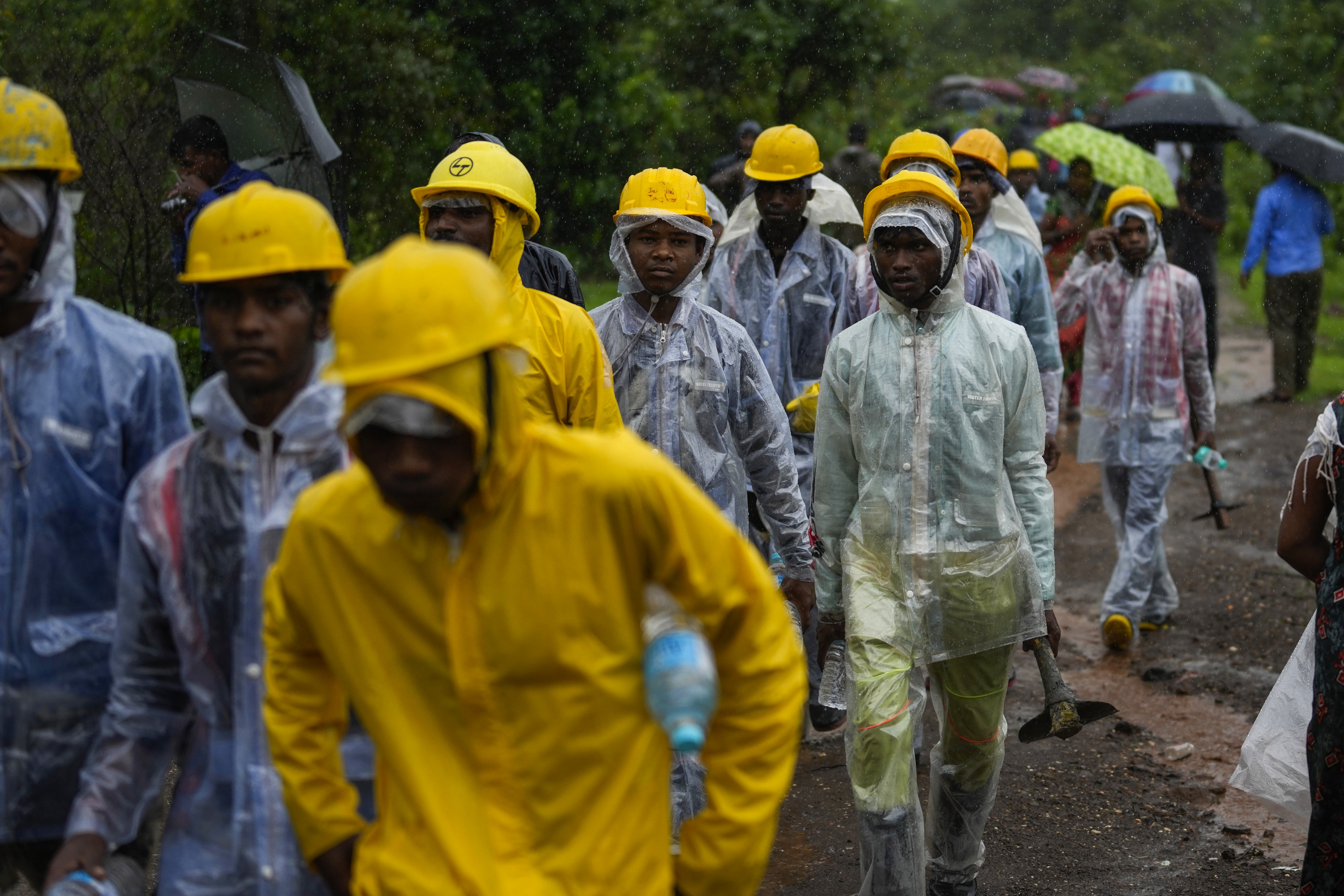 Rescuers walk toward the site of a landslide in Raigad district, western Maharashtra state, India, Thursday. While some people are reported dead many others are feared trapped under piles of debris.