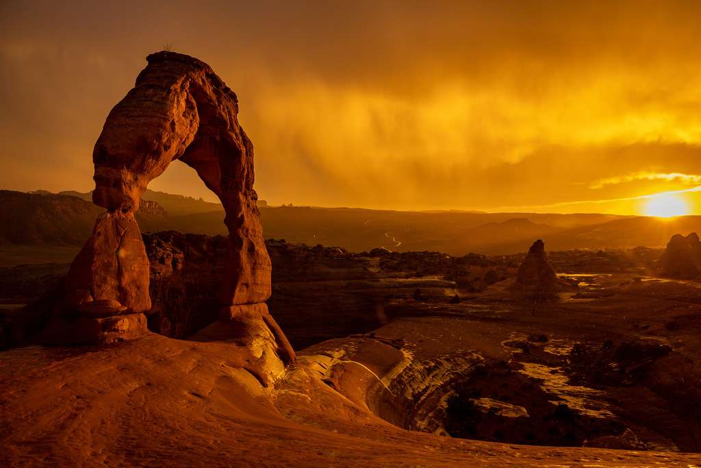 The sun sets as a rainstorm blows over Delicate Arch in Arches National Park near Moab on Sept. 18, 2021.