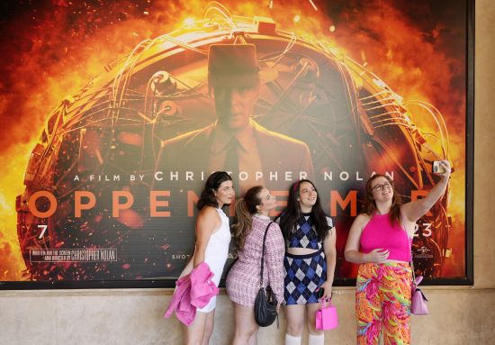 From left, Gabrielle Roitman, Kayla Seffing, Maddy Hiller and Casey Myer take a selfie in front of an "Oppenheimer" movie poster before they attended an advance screening of "Barbie," Thursday, at AMC The Grove 14 theaters in Los Angeles.