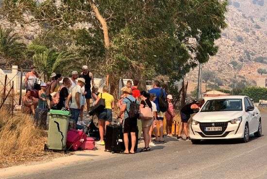 Thousands of tourists and residents fleeing wildfires on the Greek island of Rhodes took refuge in schools and shelters on Sunday, with many evacuated on private boats as flames threatened resorts and coastal villages.