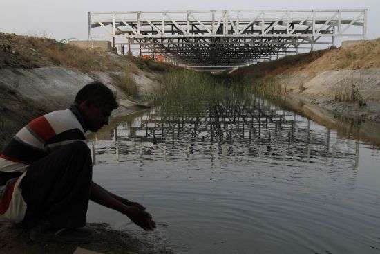 A worker washes his hands as installed solar panels are visible atop the Narmada canal at Chandrasan village, outside of Ahmadabad, India, Feb. 16, 2012. The project brings water to hundreds of thousands of villages in the dry, arid regions of western India’s Gujarat state.