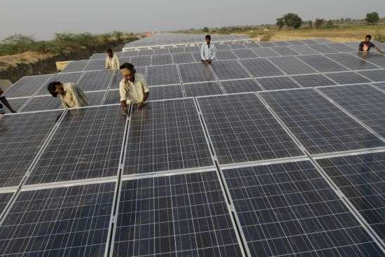 Indian laborers work amid installed solar panels atop the Narmada canal at Chandrasan village, outside Ahmadabad, India, Feb. 16, 2012. The project brings water to hundreds of thousands of villages in the dry, arid regions of western India’s Gujarat state.