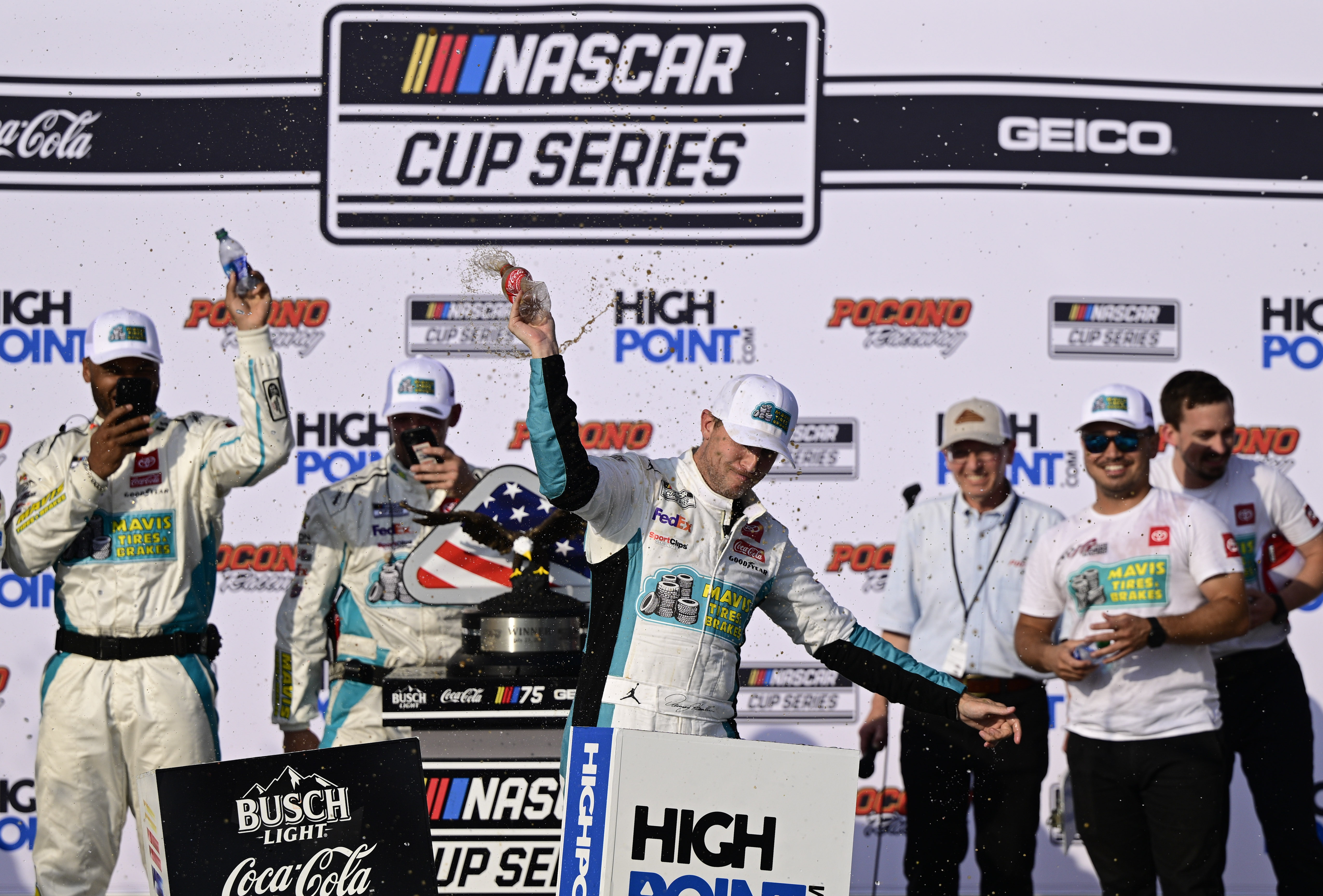Denny Hamlin, center, celebrates in Victory Lane after winning a NASCAR Cup Series auto race at Pocono Raceway, Sunday, July 23, 2023, in Long Pond, Pa. 