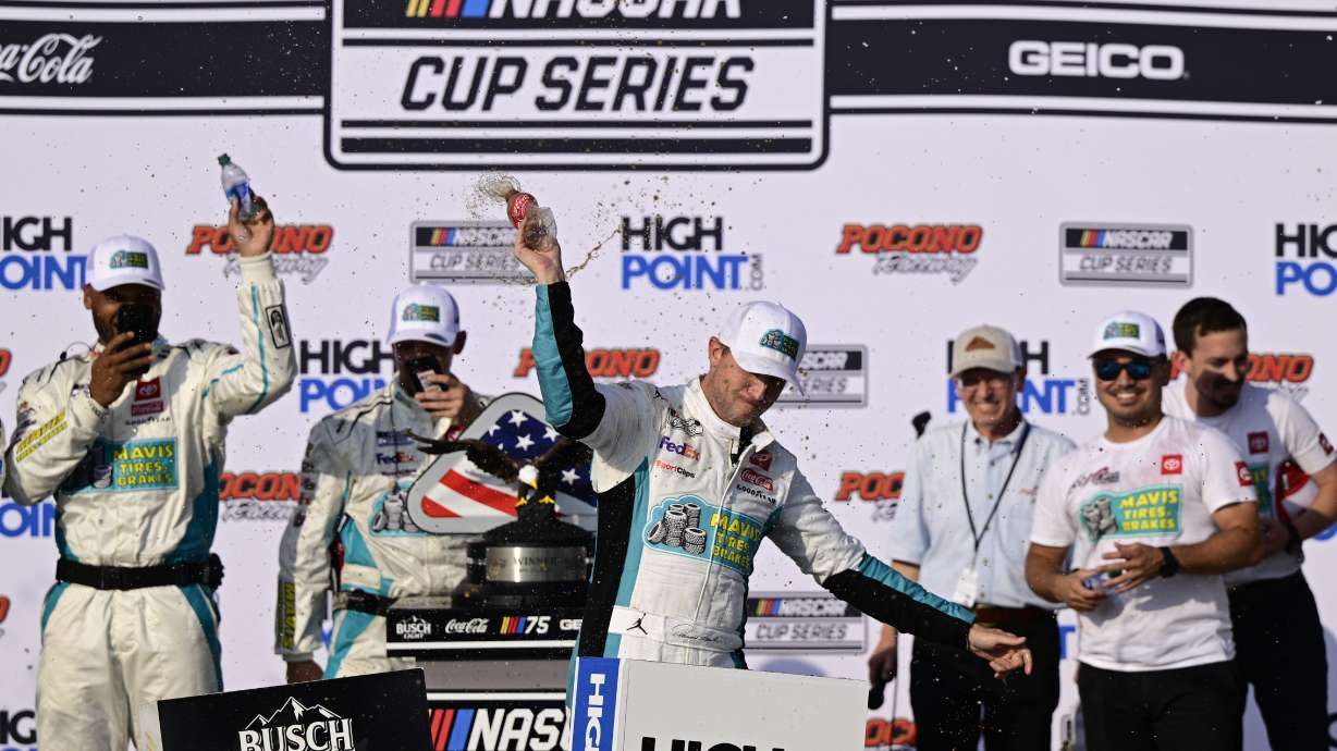 Denny Hamlin, center, celebrates in Victory Lane after winning a NASCAR Cup Series auto race at Pocono Raceway, Sunday, July 23, 2023, in Long Pond, Pa.