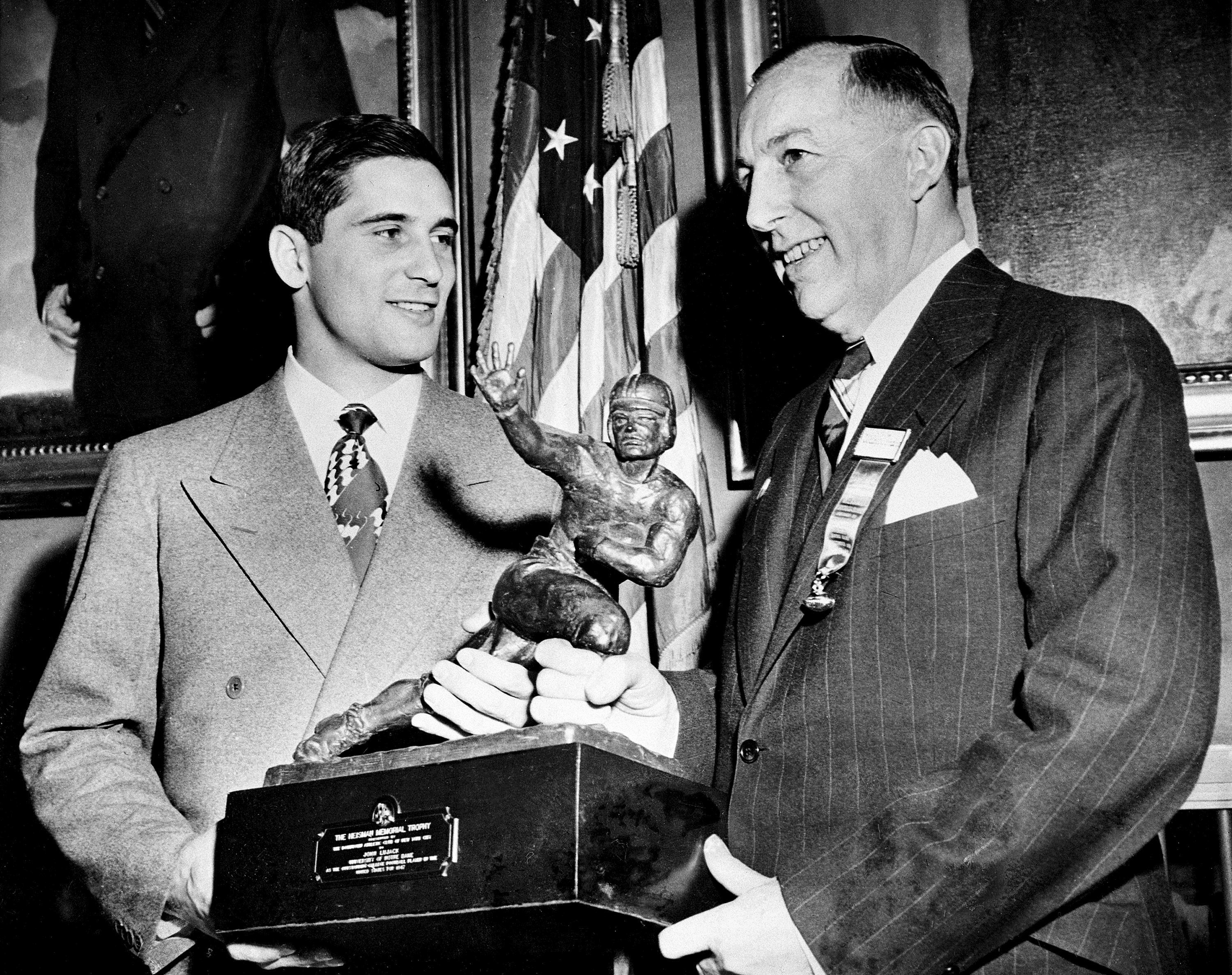 FILE - Notre Dame quarterback Johnny Lujack, left, recceives the Heisman Memorial Trophy from Wilbur Jurden, president of the Downtown Athletic Club in New York, Dec. 10, 1947. Lujack, the Heisman Trophy winner who led Notre Dame to three national championships in the 1940s, died in Florida on Tuesday, July 25, 2023, following a brief illness. He was 98. 