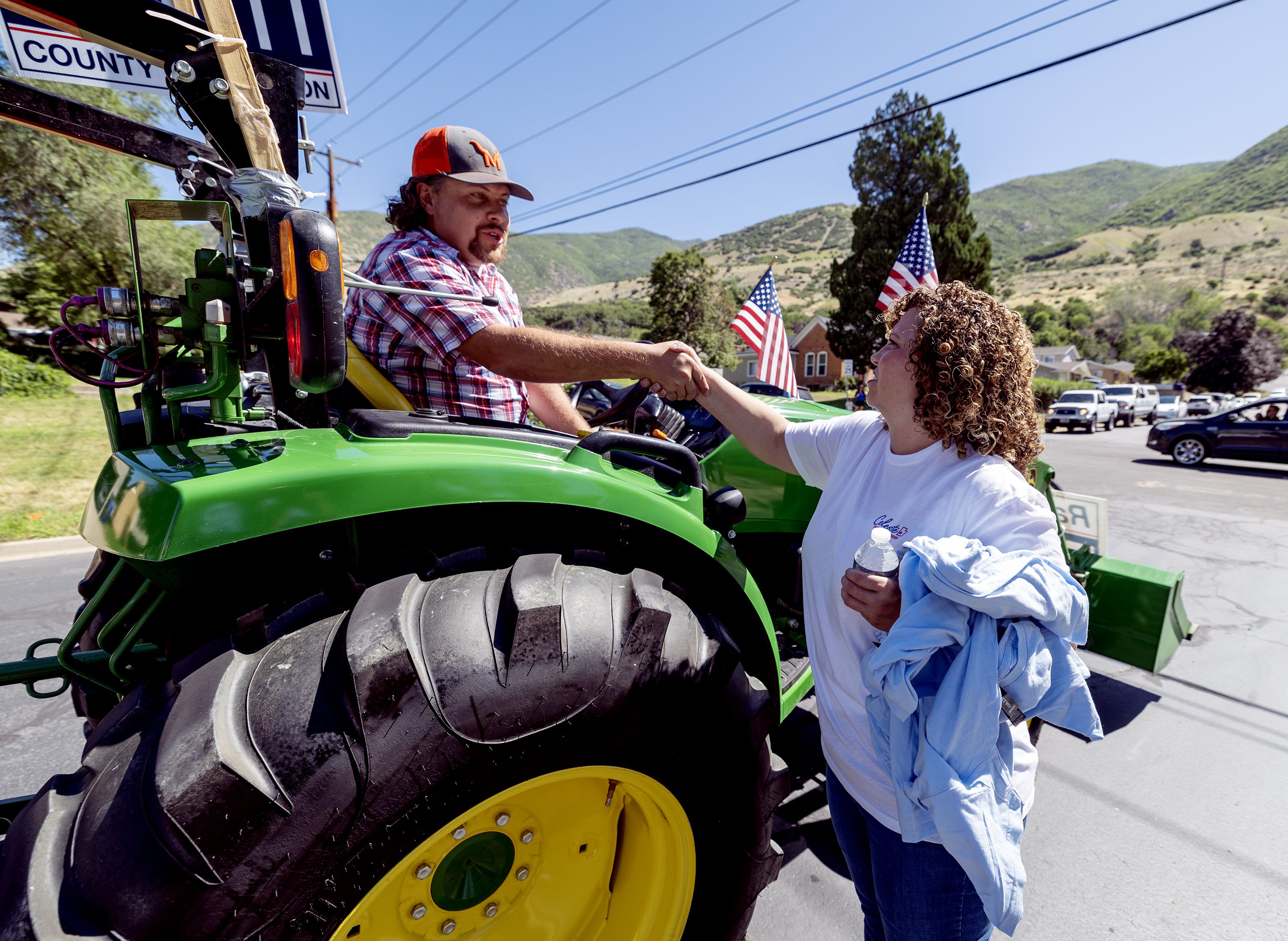 Davis County Commissioner Randy Elliott shakes hands with Celeste Maloy, congressional candidate, after Elliott drove the tractor pulling a trailer with Maloy aboard in a parade in Farmington on July 15.