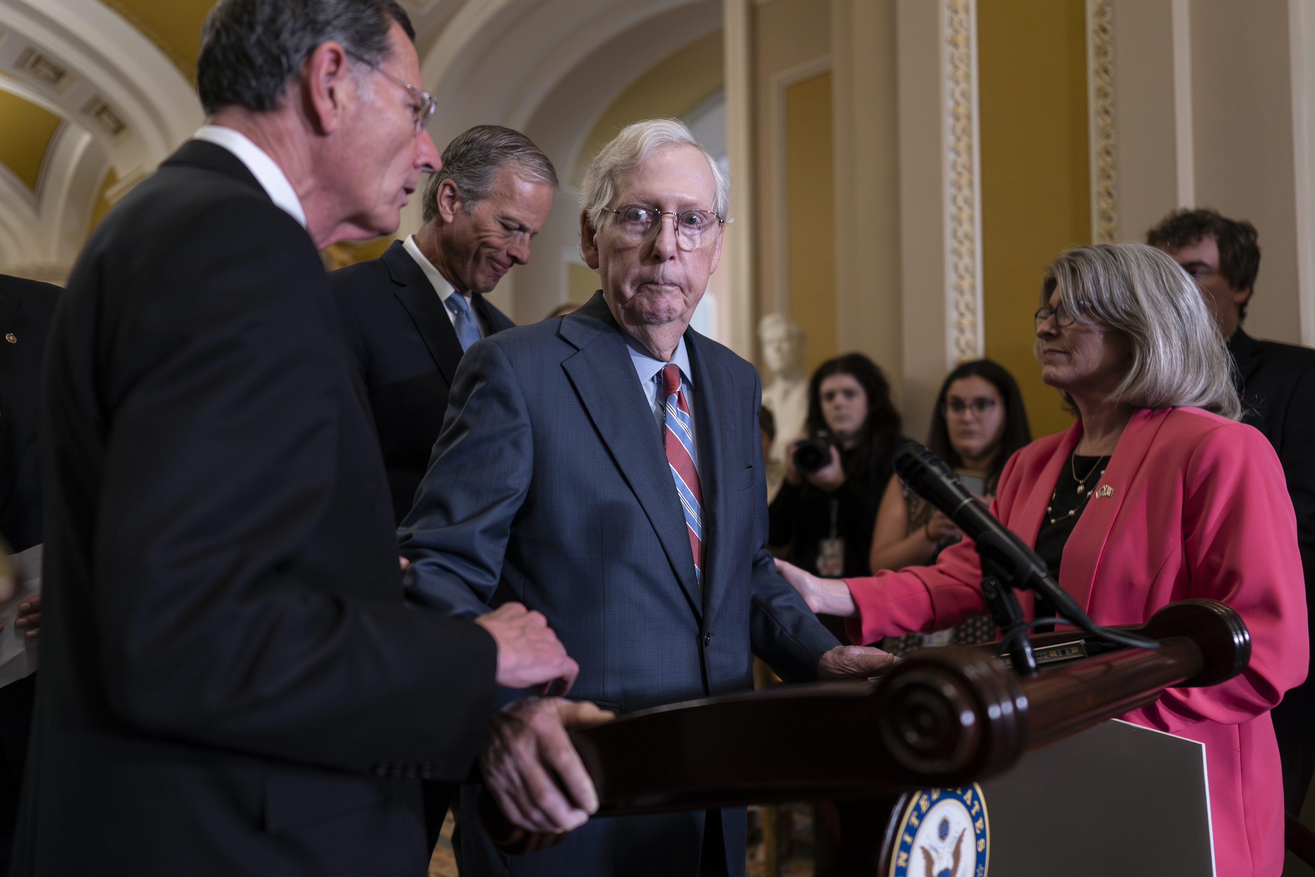 Senate Minority Leader Mitch McConnell, R-Ky., center, is helped by, from left, Sen. John Barrasso, R-Wyo., Sen. John Thune, R-S.D., and Sen. Joni Ernst, R-Iowa, after the 81-year-old GOP leader froze at the microphones in Washington on Wednesday. 