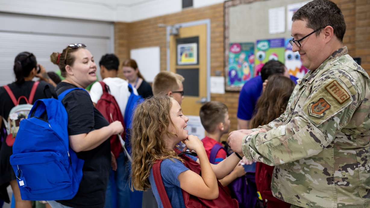 Air Force Tech Sgt. Kalin Anderson helps his daughter Karli, 8, put on a bracelet while the family collects school supplies at Operation Homefront’s annual Back-to-School Brigade at Hill Field Elementary in Clearfield on Wednesday.