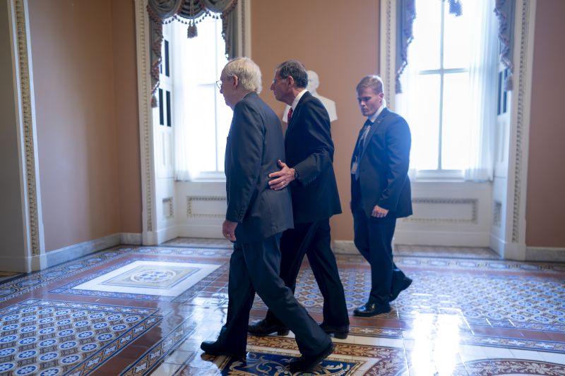 Senate Minority Leader Mitch McConnell, R-Ky., left, is assisted by Sen. John Barrasso, R-Wyo., second from right, and a Capitol Police officer after the 81-year-old GOP leader froze at the microphones as he arrived for a news conference at the Capitol in Washington, Wednesday. McConnell went to his office for a few minutes and returned to speak with reporters.
