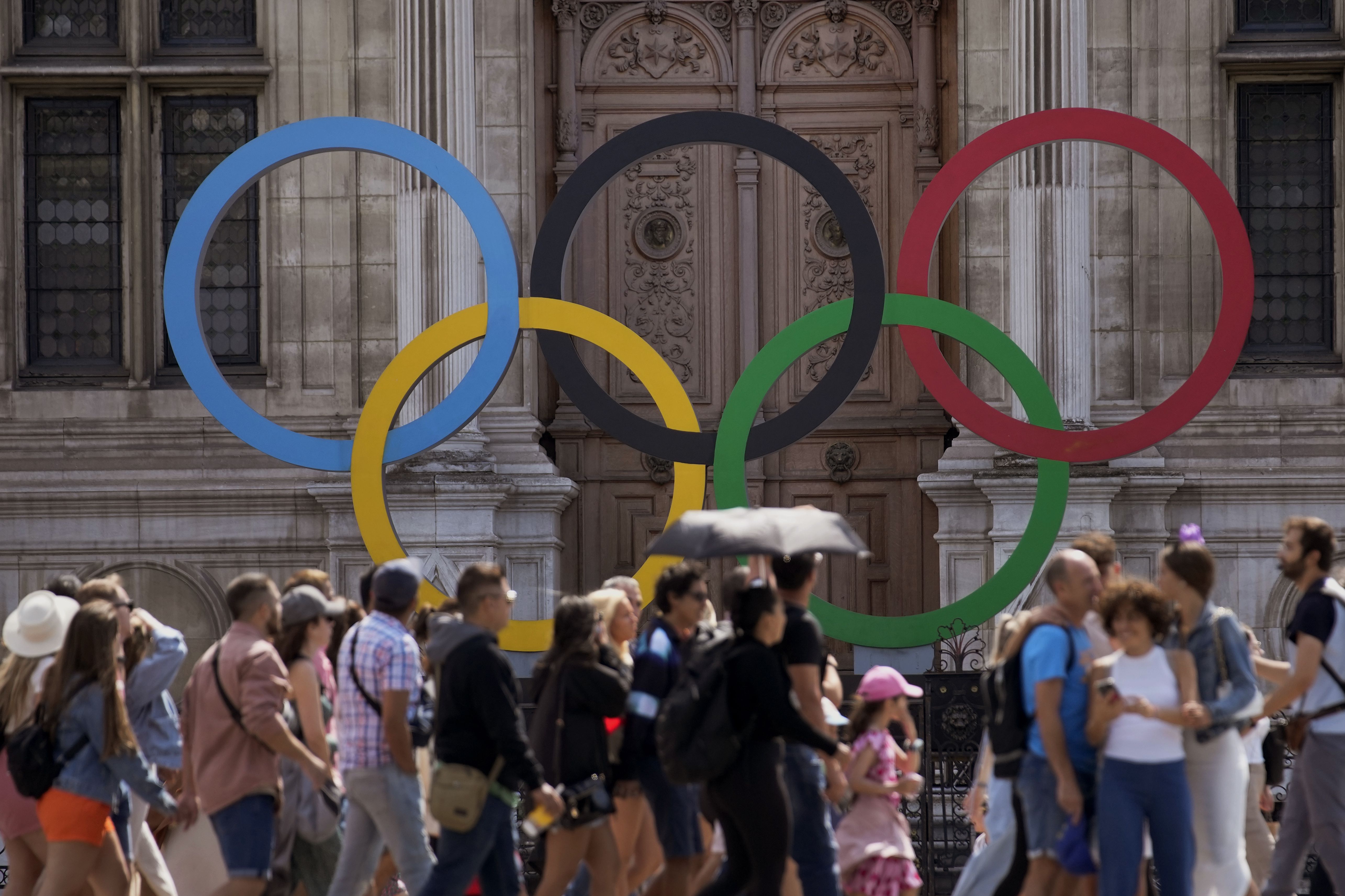 A group of tourists walk past the Olympic rings in front of the Paris City Hall with one year to until the Paris 2024 Olympic Games opening ceremony, Wednesday.