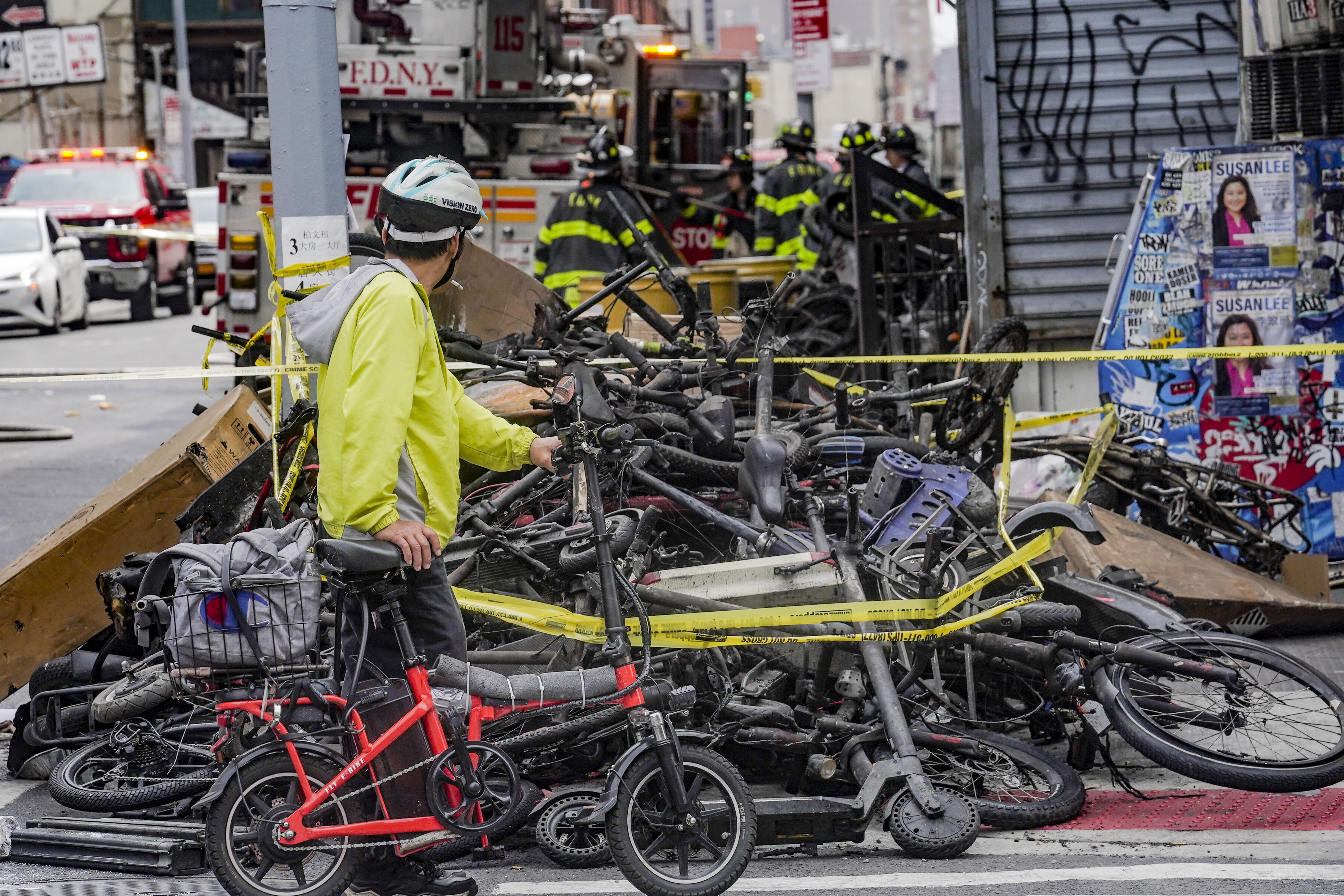 A biker stops to look at a pile of e-bikes in the aftermath of a fire in Chinatown, which started at an e-bike shop and spread to upper-floor apartments, June 20 in New York.