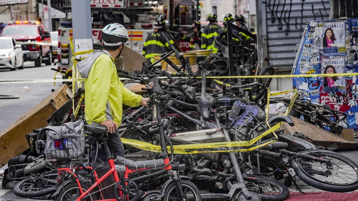 A biker stops to look at a pile of e-bikes in the aftermath of a fire in Chinatown, which started at an e-bike shop and spread to upper-floor apartments, June 20 in New York.