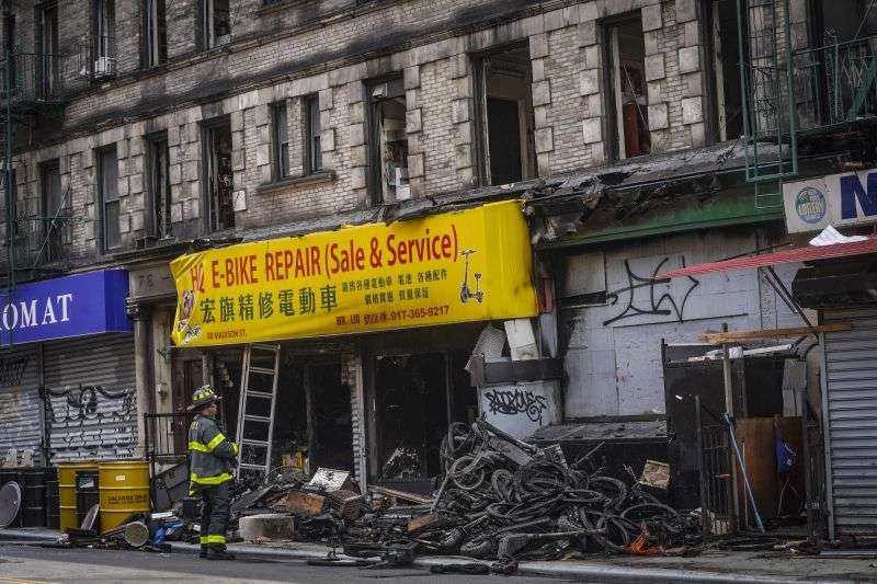 A firefighter looks through debris in the aftermath of a fire which authorities say started at an e-bike shop and spread to upper-floor apartments June 20 in New York. Federal officials are looking into cracking down on defective lithium-ion batteries that power hoverboards, scooters and motorized bicycles because of a rash of deadly fires caused by exploding batteries. The effort comes as New York City implements new laws meant to reduce the number of fires, injuries and deaths in a city where e-bikes have become ubiquitous.