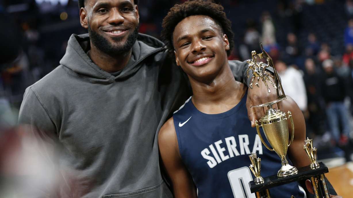 FILE - LeBron James, left, poses with his son Bronny after Sierra Canyon beat Akron St. Vincent - St. Mary in a high school basketball game, Saturday, Dec. 14, 2019, in Columbus, Ohio. Bronny James, son of NBA superstar LeBron James, was hospitalized after going into cardiac arrest while participating in a practice at Southern California on Monday, July 24, 2023.