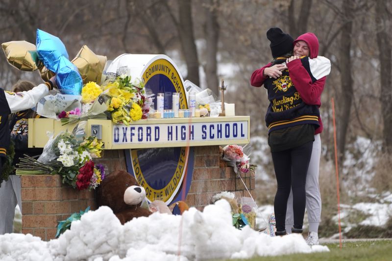 Students hug at a memorial following a shooting at Oxford High School in Oxford, Mich., Dec. 1, 2021. A judge in Michigan must decide in a hearing that starts Thursday whether teenager Ethan Crumbley who killed four students at the school should spend his life in prison.