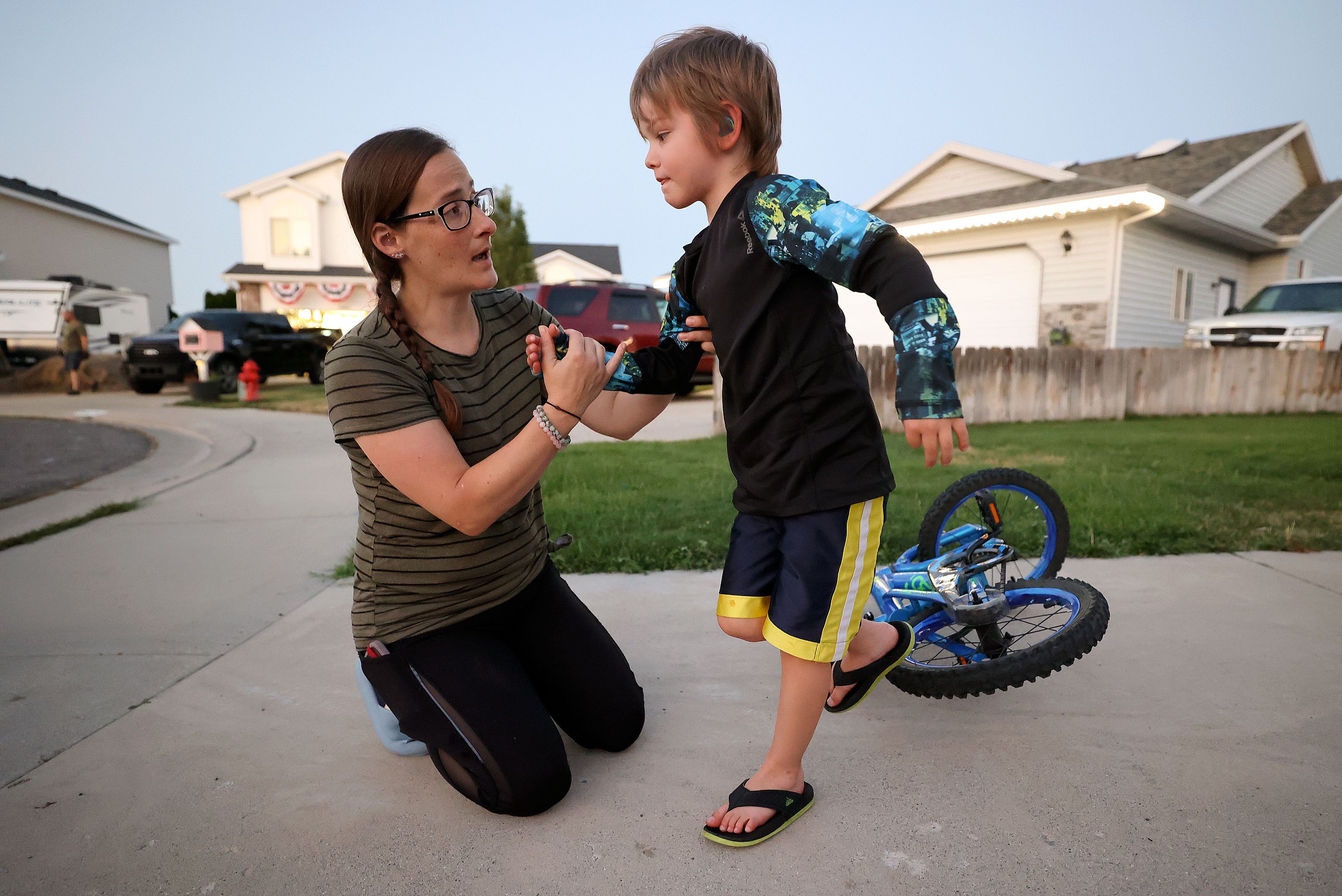 Kerra Davis helps her son Reed Davis after he fell off his bike outside their home in West Jordan on July 21. Davis, a mother of three, uses medical cannabis to treat chronic pain from endometriosis, pelvic congestion syndrome and arthritis.