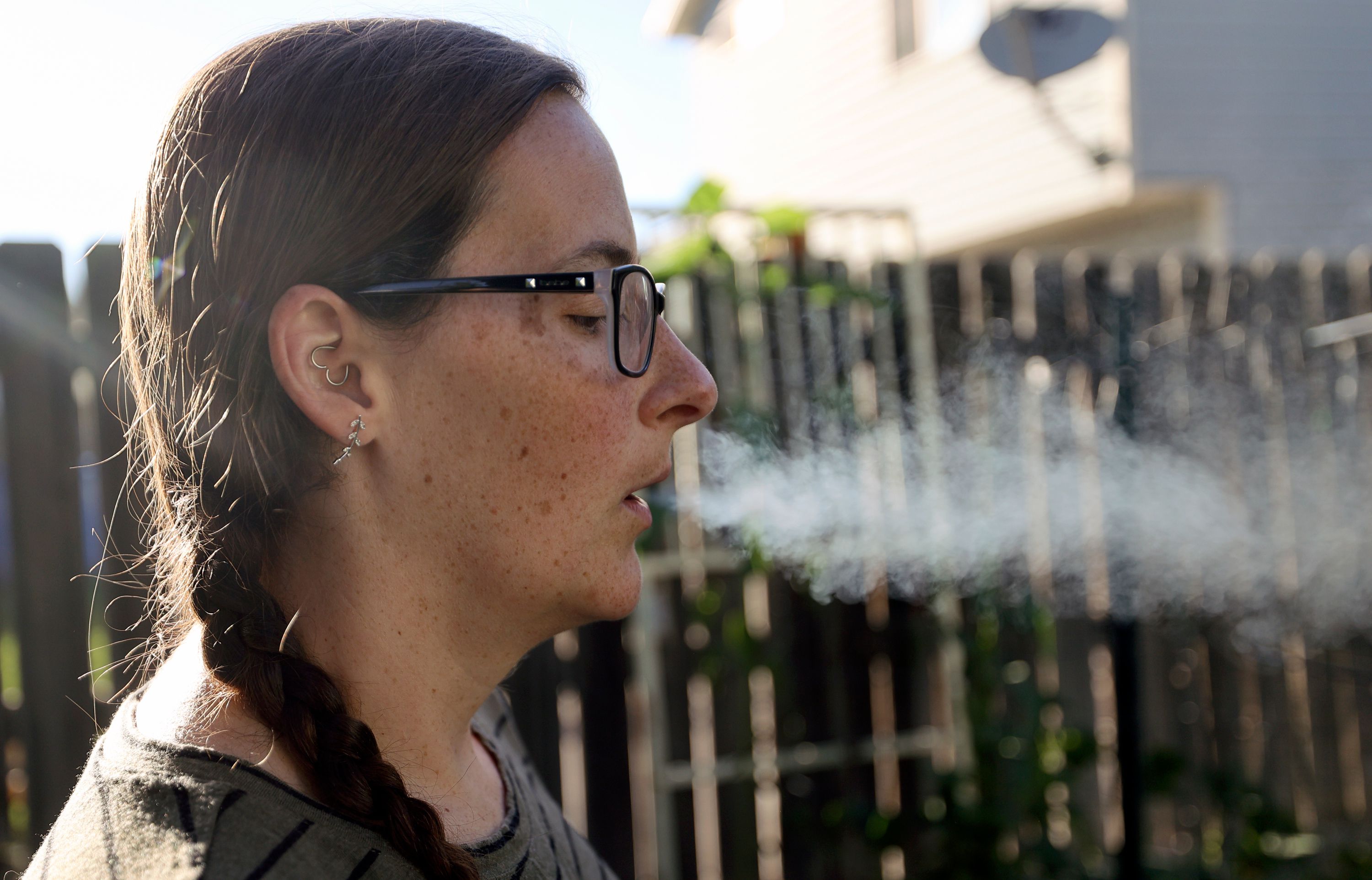 Kerra Davis exhales after using a medical cannabis vape pen outside her home in West Jordan on July 21. Davis, a mother of three, uses medical cannabis to treat chronic pain from endometriosis, pelvic congestion syndrome and arthritis.