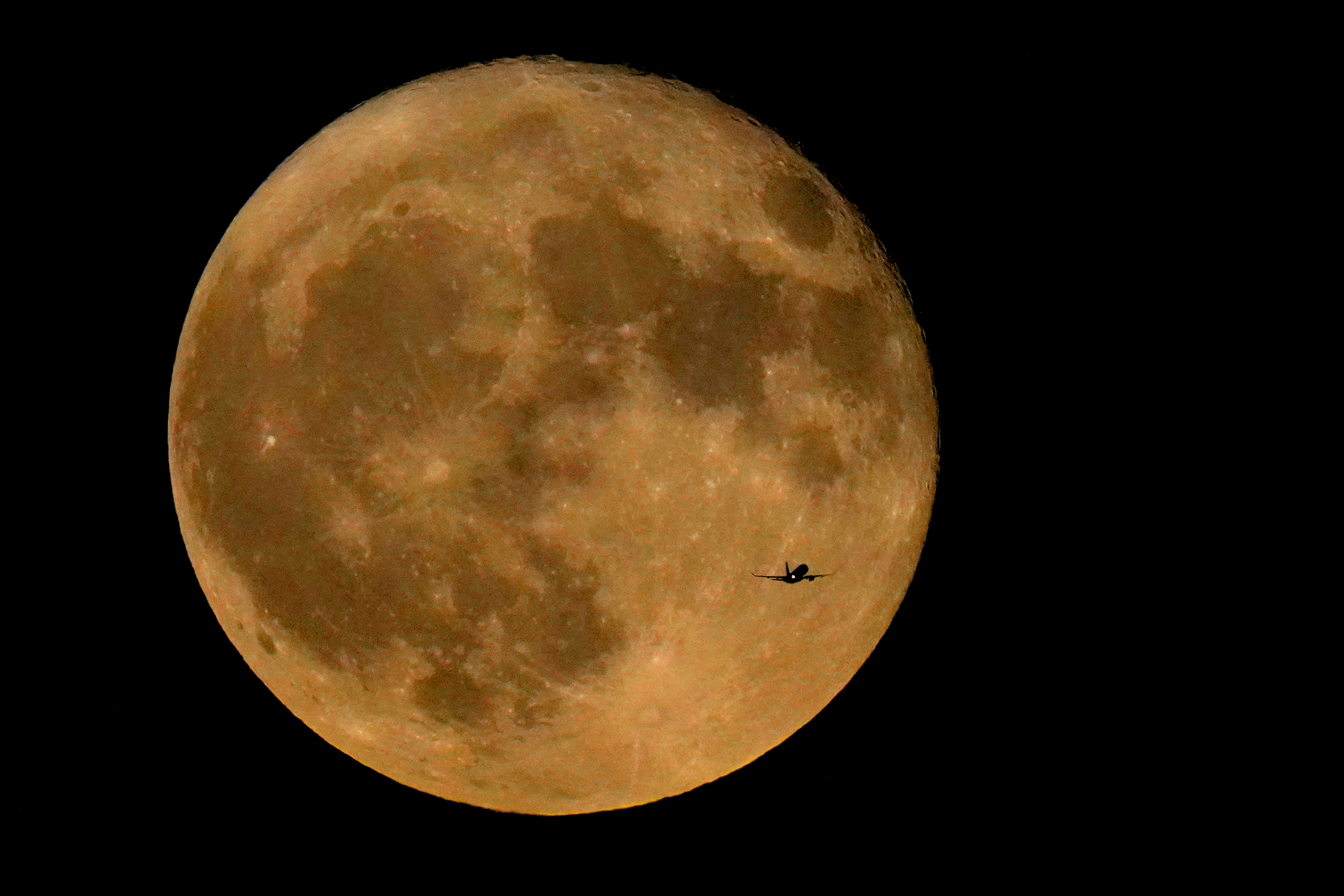 A commercial airliner flies Northwest across Lake Michigan in front of the "Full Buck" supermoon, the first of four supermoons in 2023, July 3, 2023, in Chicago. The cosmos is offering up a double feature in August: a pair of supermoons. Catch the first show Aug. 1, as the full moon rises in the southeast. 