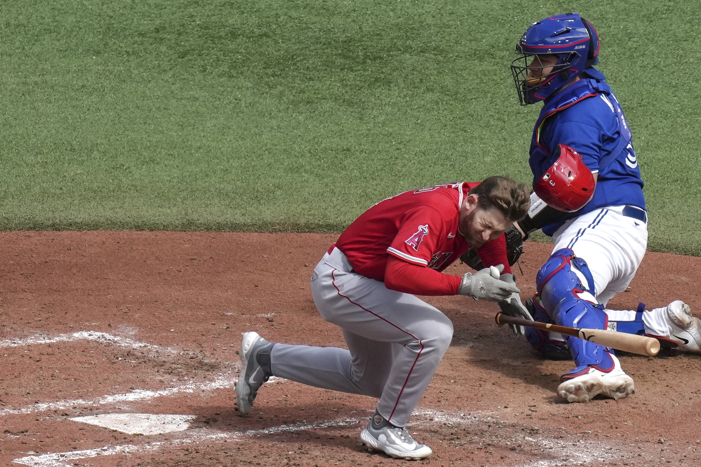 Los Angeles Angels' Taylor Ward reacts after being hit by a pitch from Toronto Blue Jays' Alek Manoah, as Blue Jays catcher Alejandro Kirk looks on during the fifth inning of a baseball game in Toronto, Saturday, July 29, 2023. 