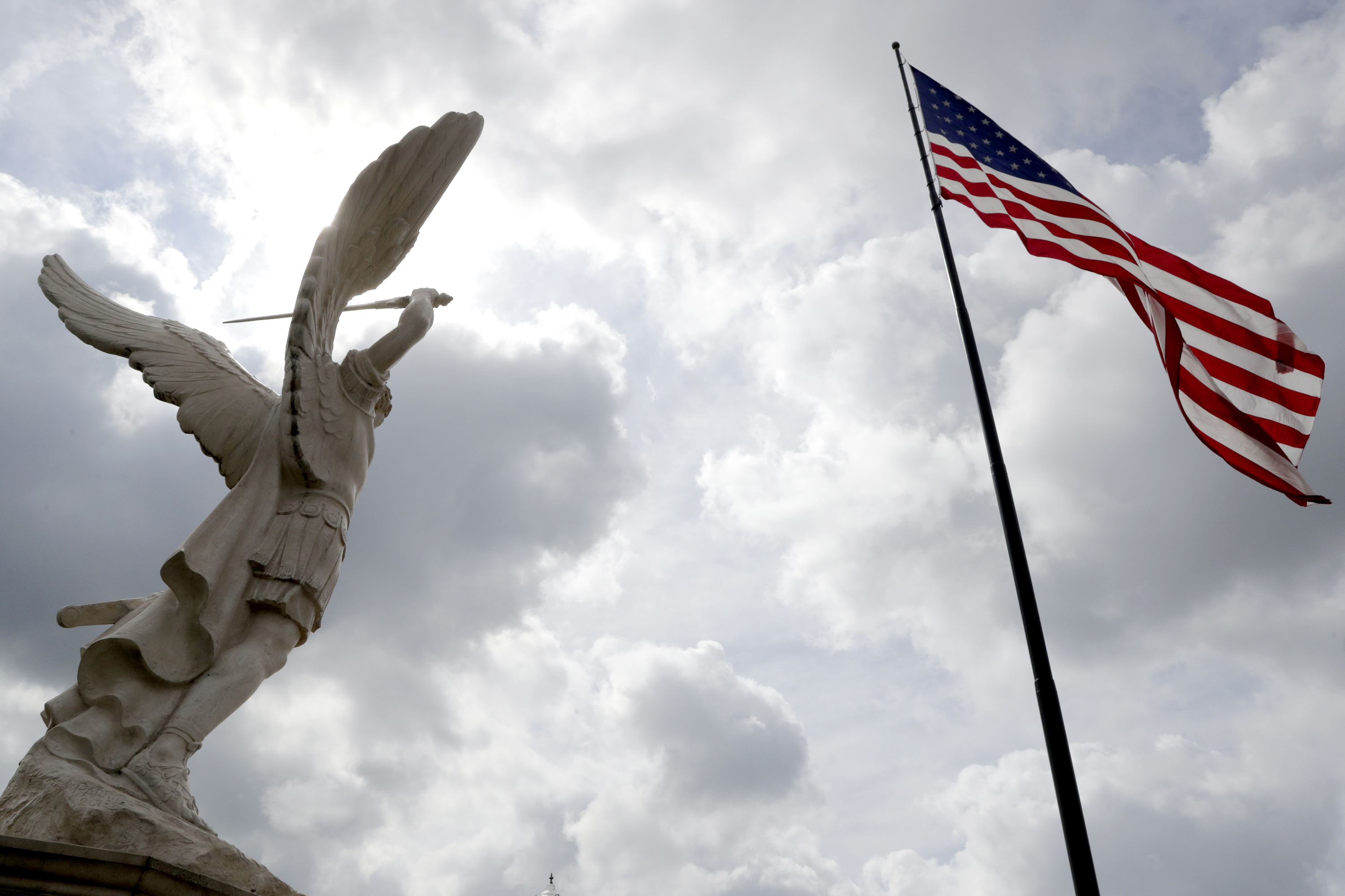 A statue of Archangel Michael, left, stands near a large United States flag at Russell Salvatore's Patriots and Heroes Park, Aug. 10, 2018, in Buffalo, N.Y.
