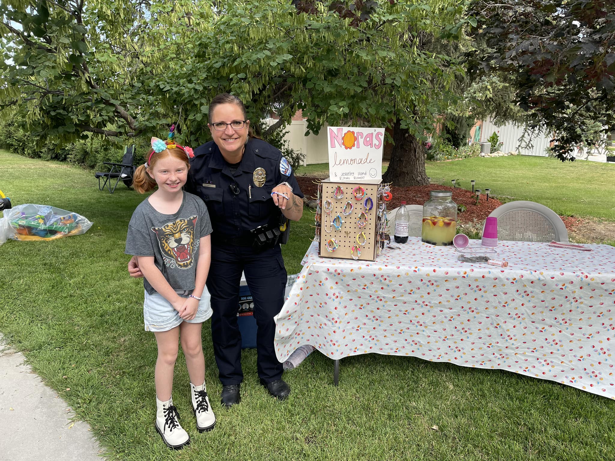 Brigham City Master Officer Crystal Beck buys a bracelet from a girl July 29 as part of a Box Elder County contest to see which police department could visit the most lemonade stands during the month of July. Tremonton-Garland police won with 54 stand visits.