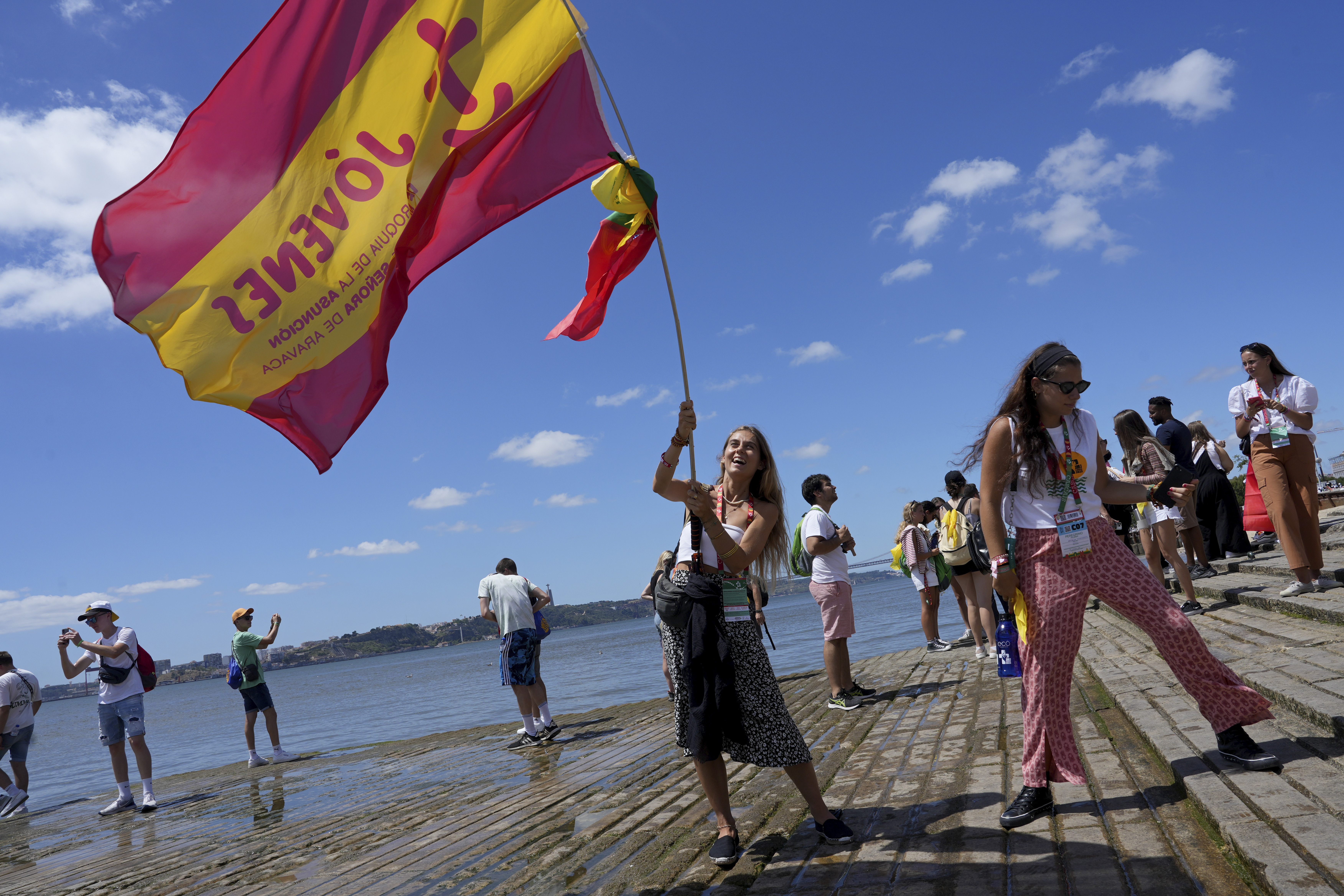 A World Youth Day pilgrim waves a Spanish flag by the water on the Tagus river bank Comercio square in Lisbon, Tuesday. Pope Francis arrived in Portugal on Wednesday to attend the international event that goes on until Aug. 6.