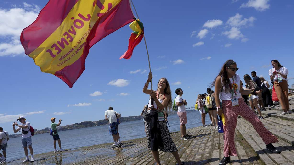 A World Youth Day pilgrim waves a Spanish flag by the water on the Tagus river bank Comercio square in Lisbon, Tuesday. Pope Francis arrived in Portugal on Wednesday to attend the international event that goes on until Aug. 6.