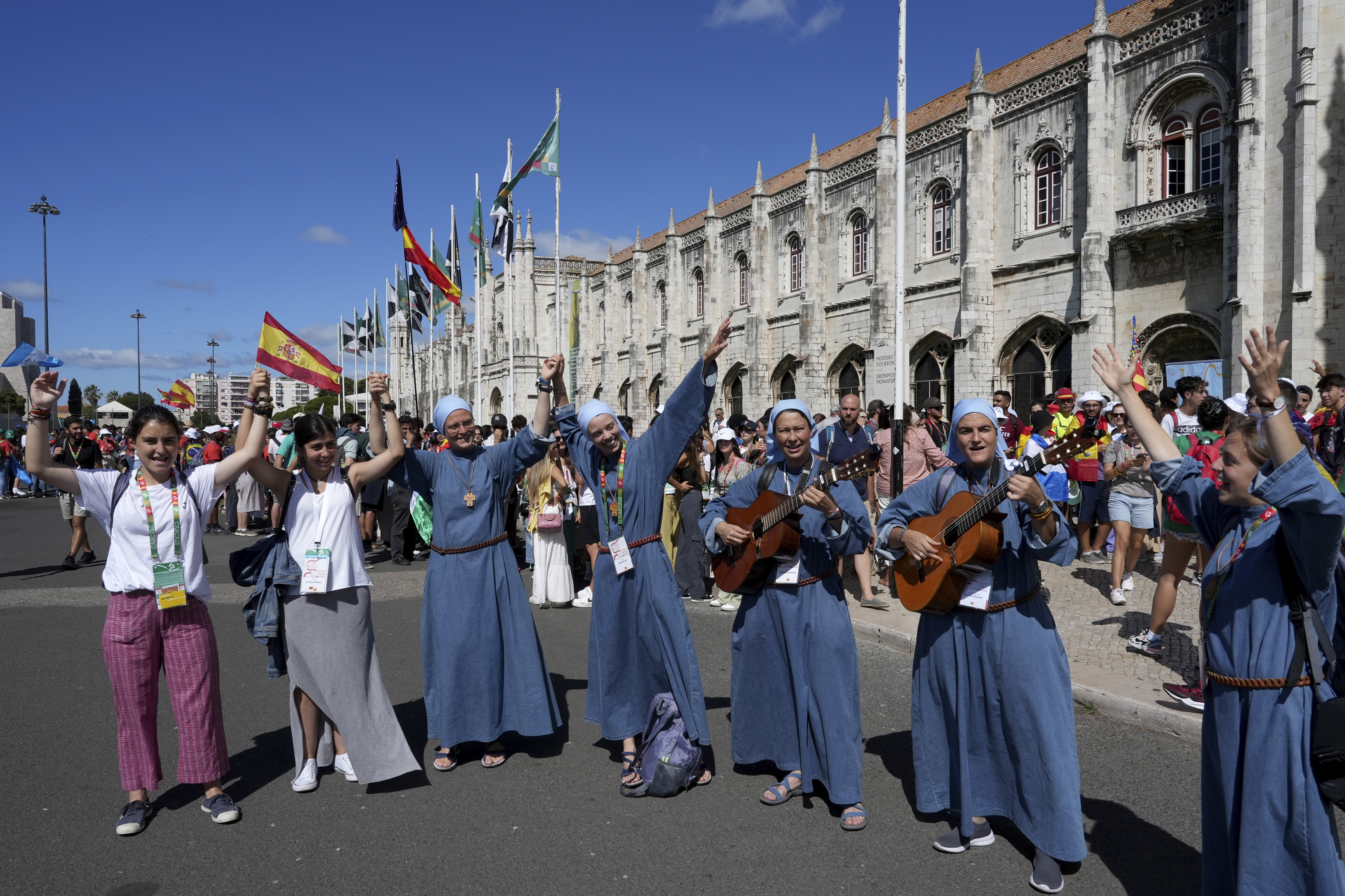 A group of nuns from Spain travelling to participate in World Youth Day sing while waiting in line to visit the 16th century Jeronimos monastery, in the background, in Lisbon, Tuesday. Pope Francis will visit the monastery when he arrives Aug. 2 to attend the international event that is expected to bring hundreds of thousands of young Catholic faithful to Lisbon and goes on until Aug. 6.