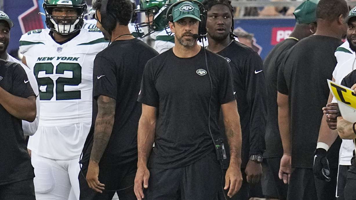 New York Jets quarterback Aaron Rodgers, center, stands on the sideline during the first half of the team's Hall of Fame NFL football preseason game against the Cleveland Browns , Thursday, Aug. 3, 2023, in Canton, Ohio.