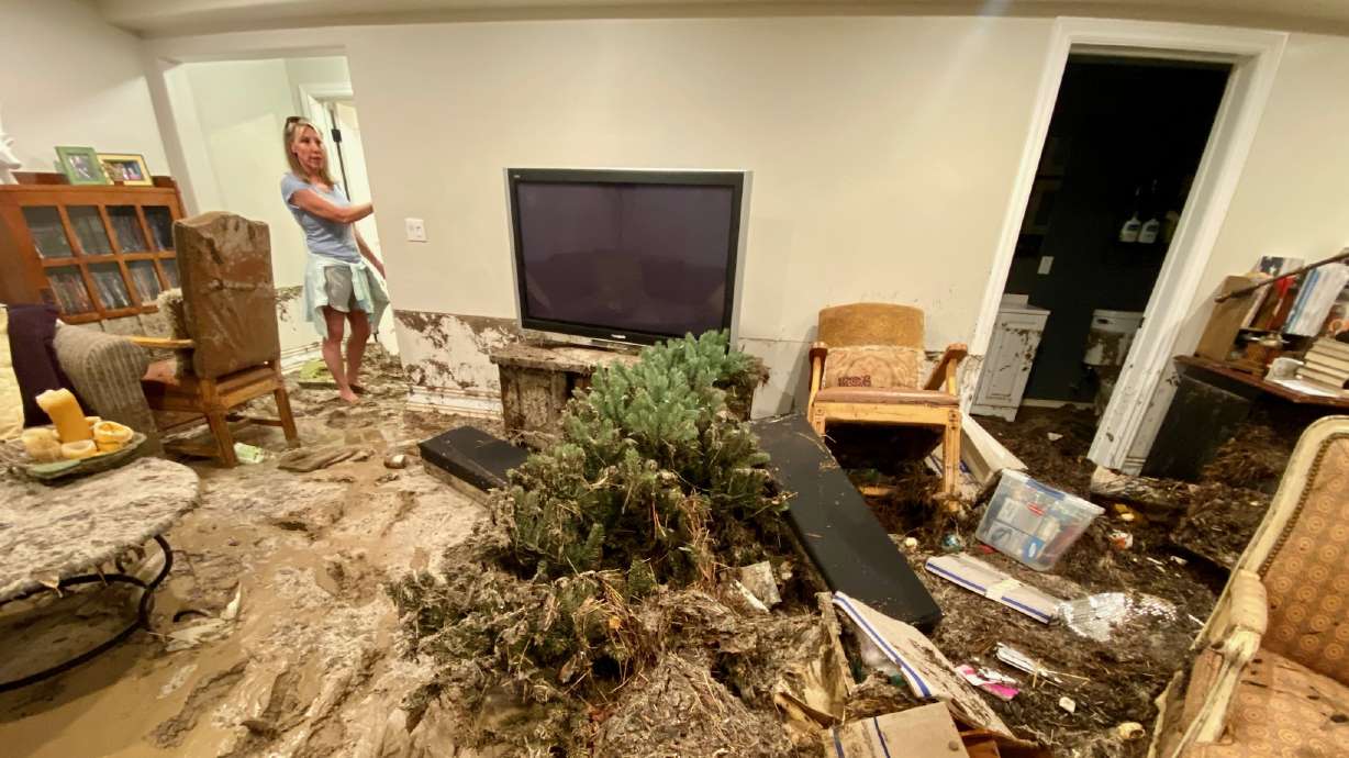 Brenda Taylor stands in the flooded home of a friend's basement in Draper on Friday.