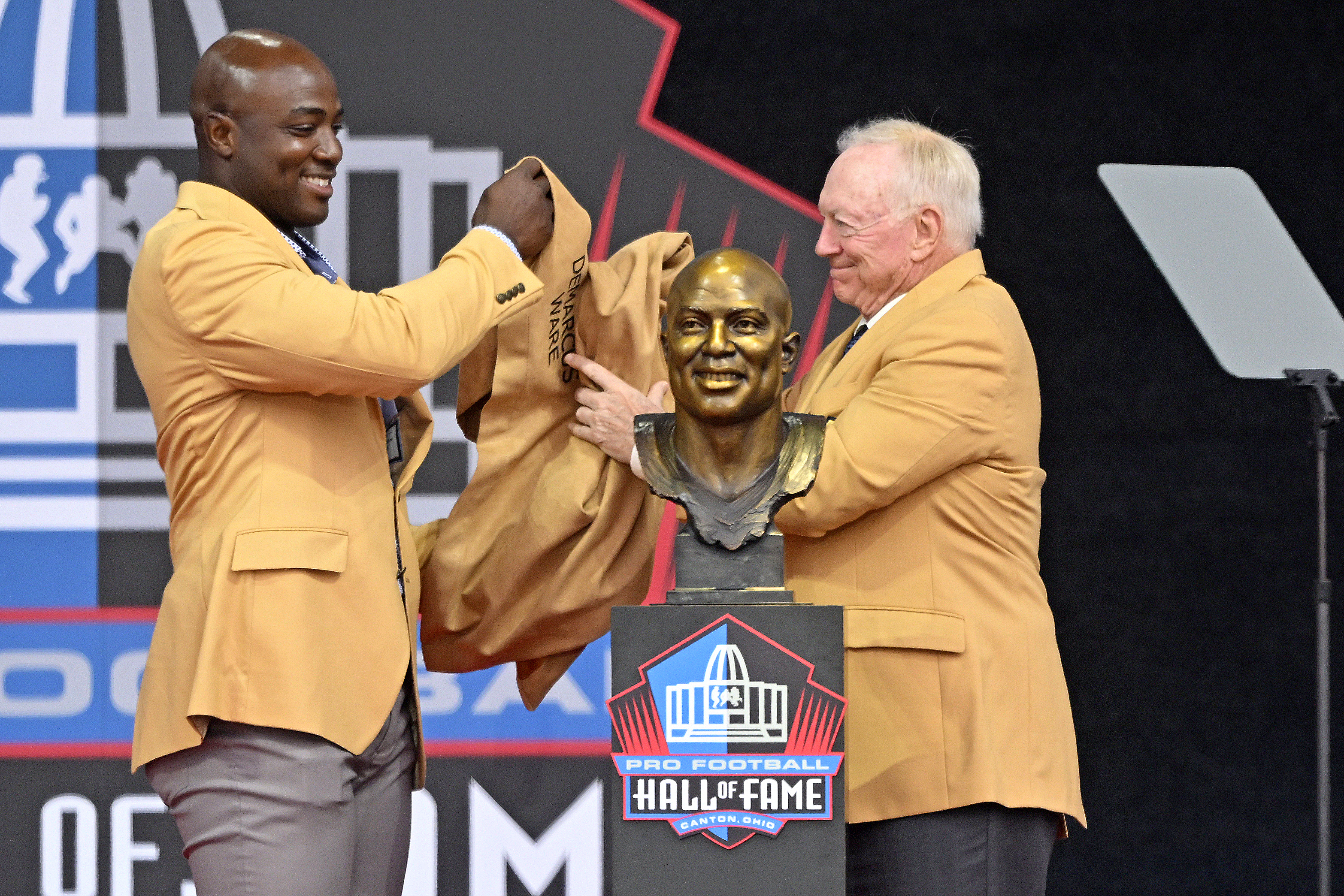 Former NFL player DeMarcus Ware, left, and Jerry Jones unveil Ware's bust speaks during his induction into the Pro Football Hall of Fame in Canton, Ohio, Saturday, Aug. 5, 2023.