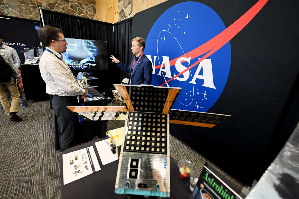 Gerard Peltzer, left, with NOAH, and Sig Lokensgard, with the NASA Ames Research Center, talk while attending the Small Satellite Conference at Utah State University in Logan on Monday.