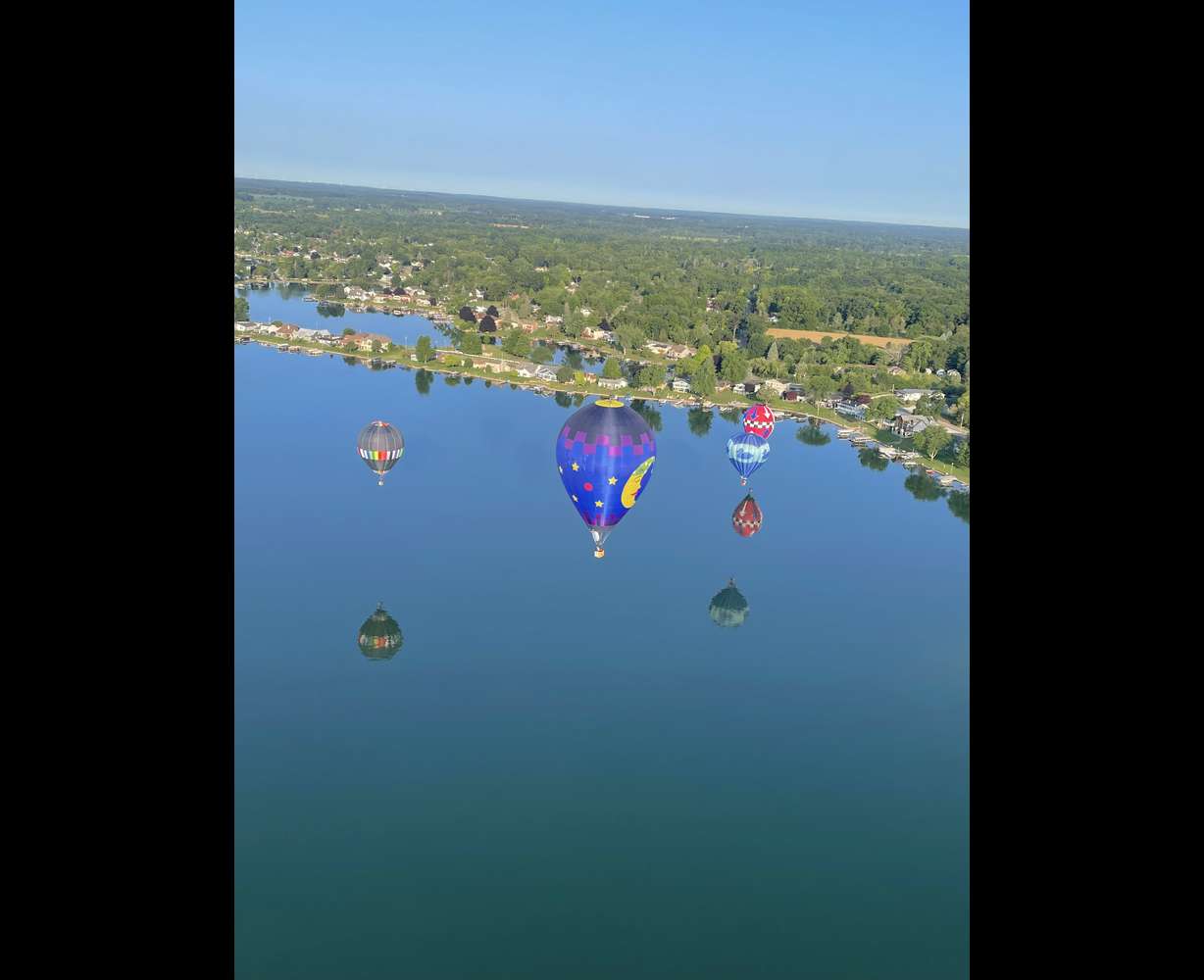 A group of hot air balloons fly over a lake at the Women's National Competition in Jackson, Missouri, in July.