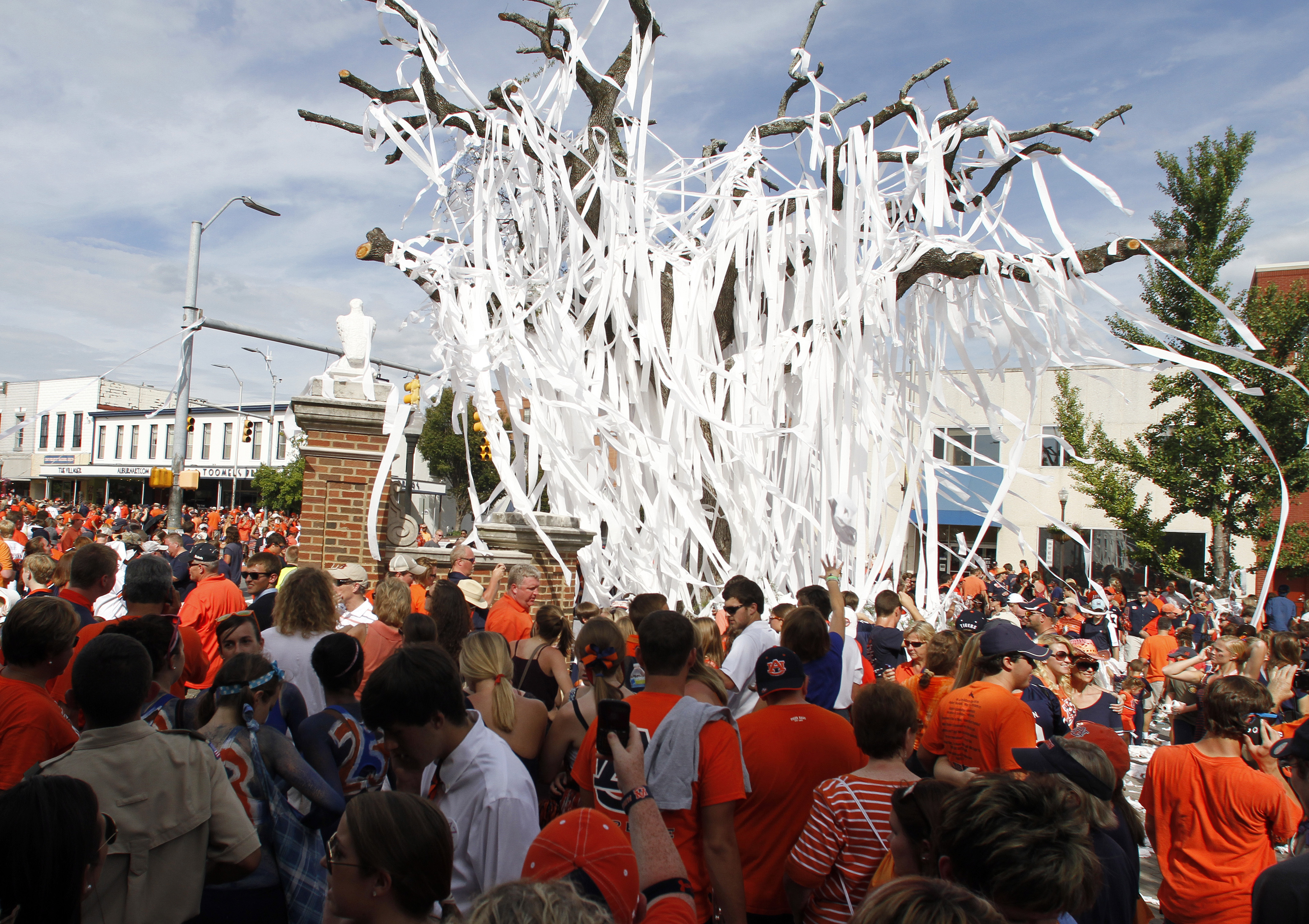 FILE - Auburn fans roll the iconic oak trees at Toomer's Corner with toilet paper after beating Lousiana-Monroe 31-28 in overtime of an NCAA college football game in Auburn, Ala., Sept. 15, 2012. Auburn fans will once again be able to celebrate victories by rolling the oak trees at Toomer’s Corner with toilet paper. Auburn had asked fans not to roll the new trees after their planting in Feburary 2017 until they were established enough to avoid damage. 